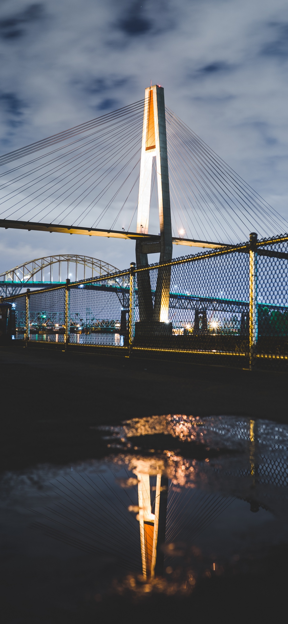 Brücke Über Wasser Während Der Nacht Night. Wallpaper in 1125x2436 Resolution