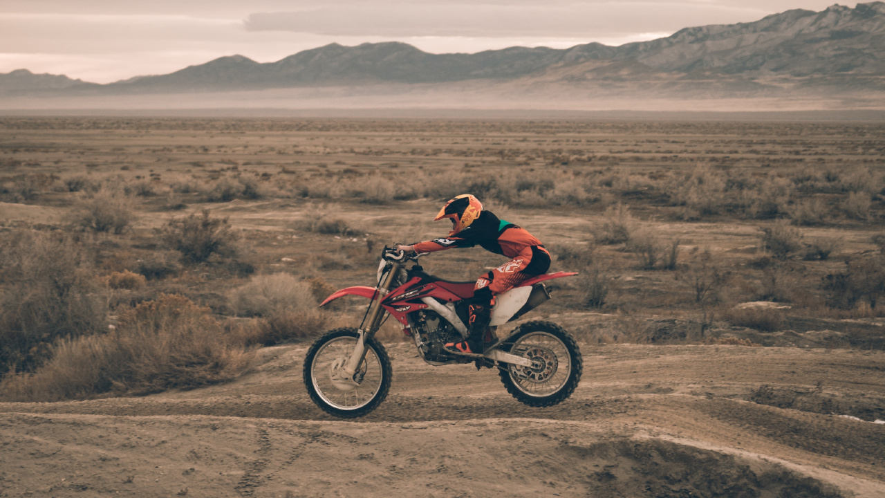 Hombre de Chaqueta Roja en Motocicleta Roja en Campo Marrón Durante el Día. Wallpaper in 1280x720 Resolution