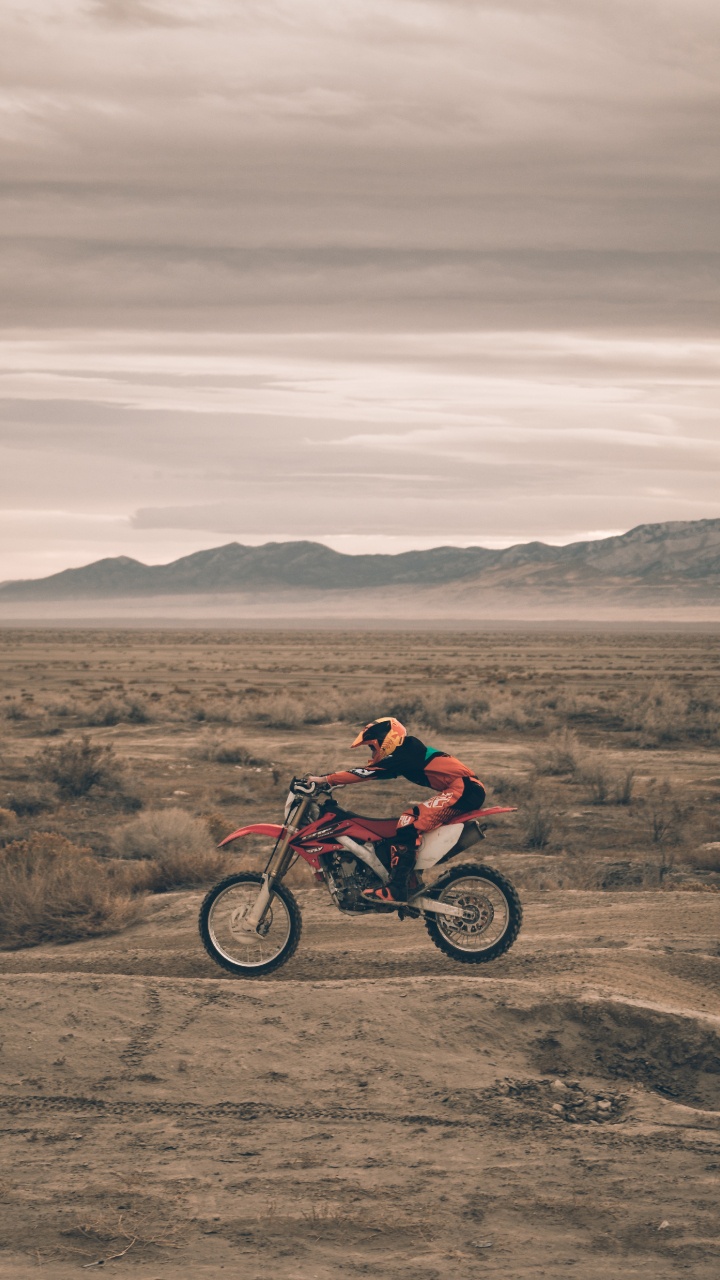 Hombre de Chaqueta Roja en Motocicleta Roja en Campo Marrón Durante el Día. Wallpaper in 720x1280 Resolution