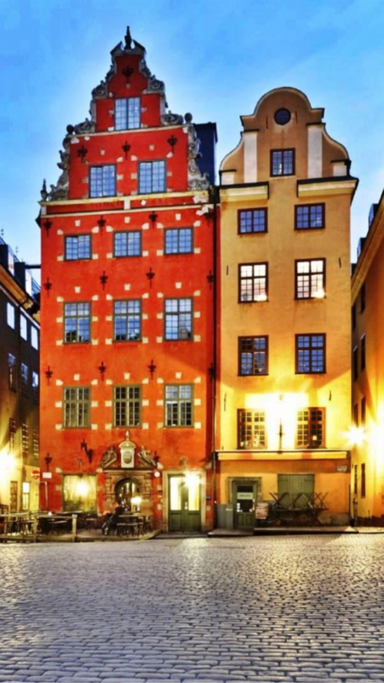 Gelbes Und Grünes Betongebäude in Der Nähe Eines Gewässers Während Der Nacht. Wallpaper in 750x1334 Resolution