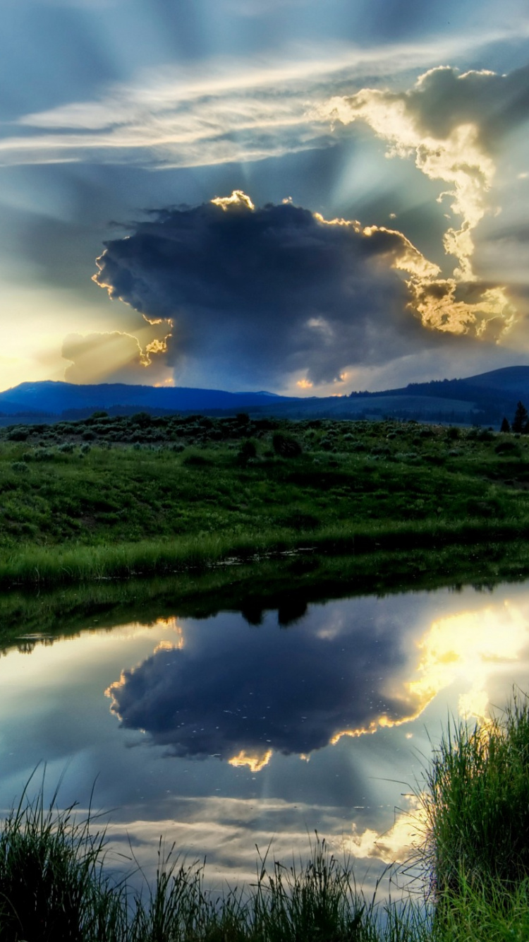 Green Grass Field Near Lake Under Cloudy Sky During Daytime. Wallpaper in 750x1334 Resolution