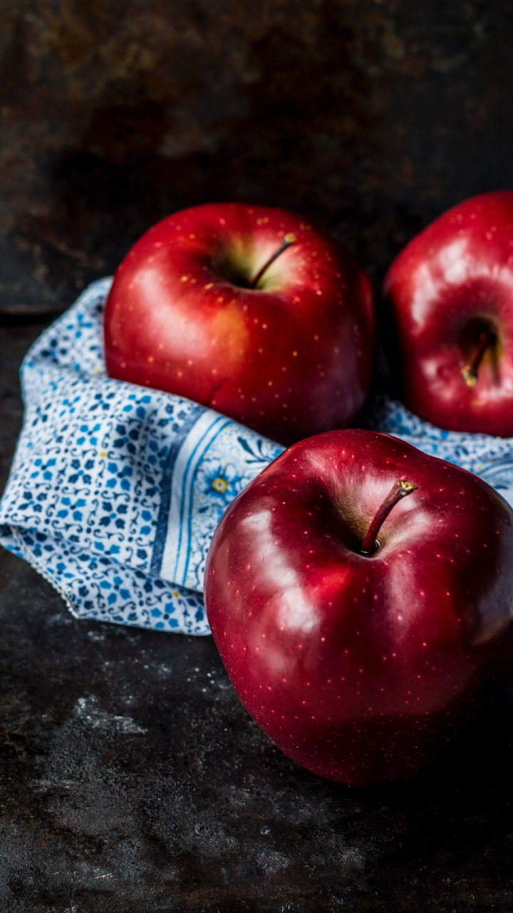 Roter Apfel Auf Blauem Und Weißem Textil. Wallpaper in 720x1280 Resolution