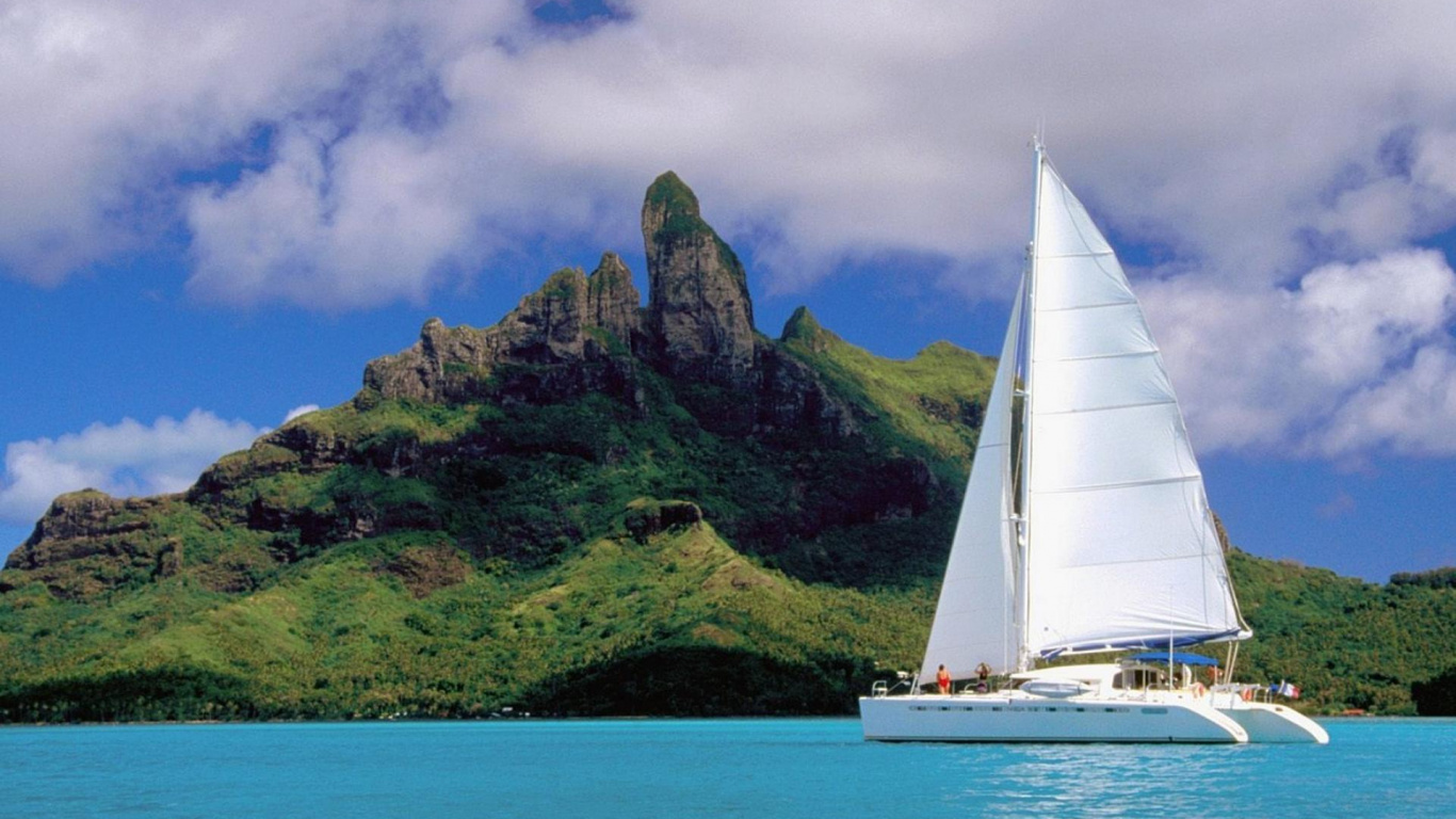 Velero Blanco en el Mar Cerca de la Montaña Verde Bajo Nubes Blancas y Cielo Azul Durante el Día. Wallpaper in 1366x768 Resolution