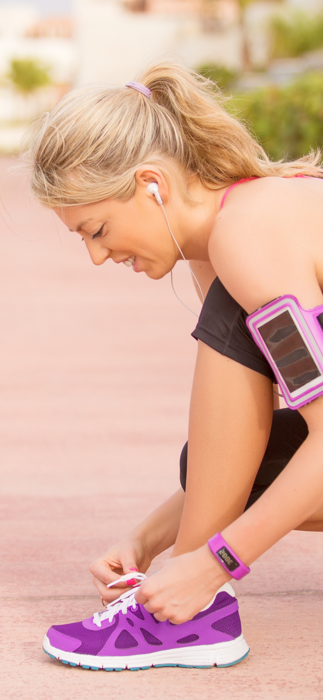 Woman in Pink Tank Top and Purple Nike Athletic Shoes Sitting on Brown Wooden Floor During. Wallpaper in 1125x2436 Resolution