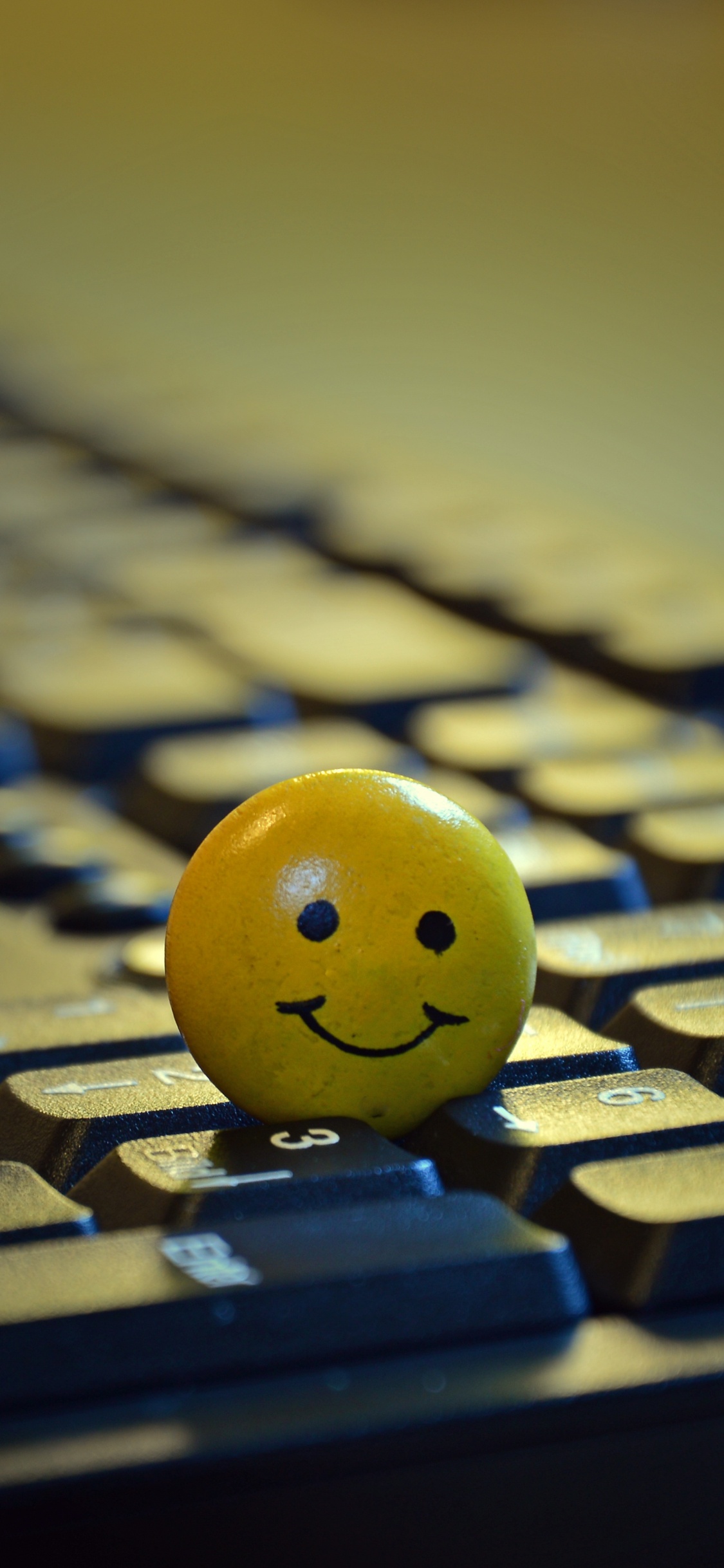 Yellow Smiley Ball on Black Computer Keyboard. Wallpaper in 1125x2436 Resolution