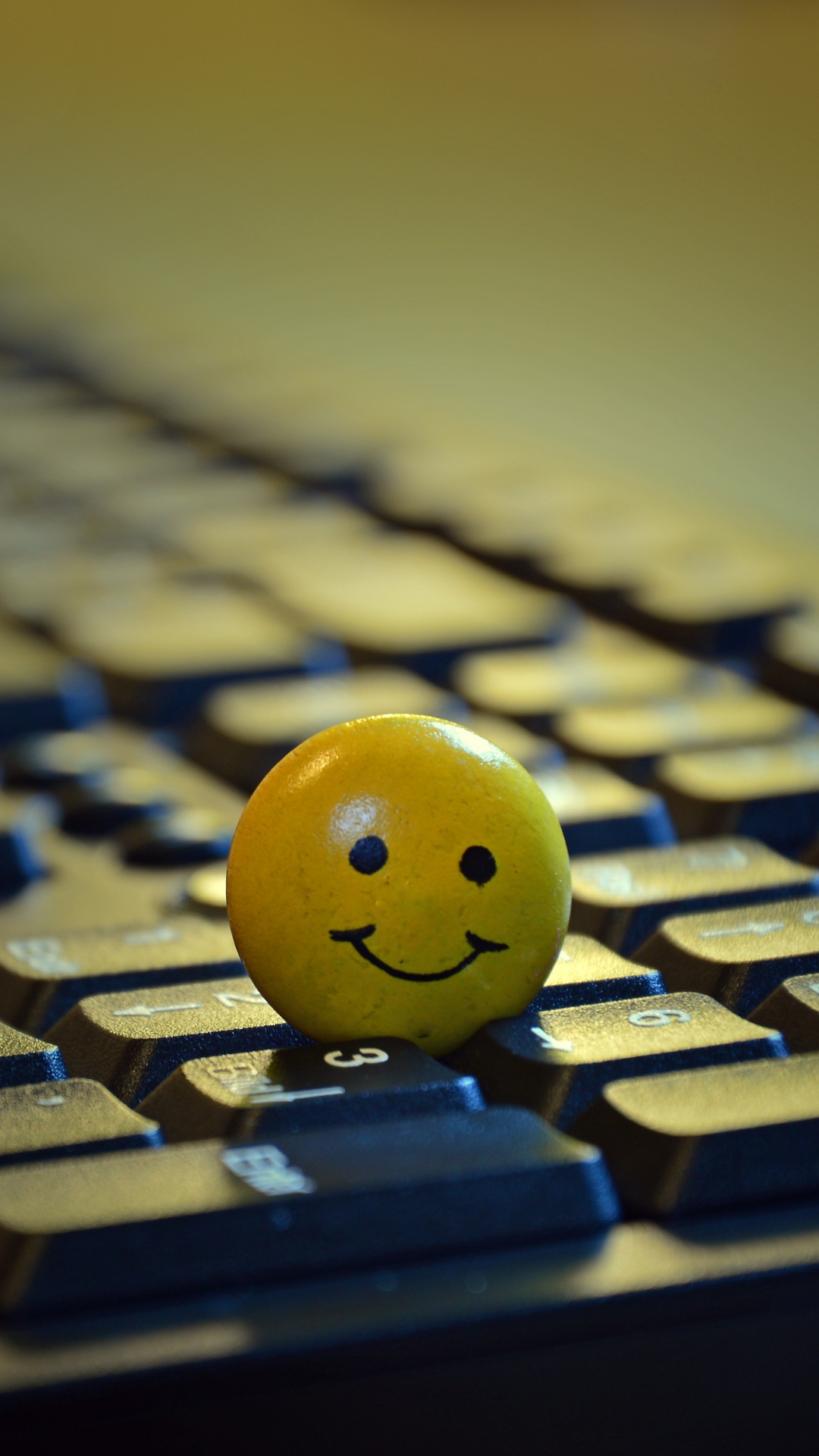 Gelber Smiley-Ball Auf Schwarzer Computertastatur. Wallpaper in 1080x1920 Resolution