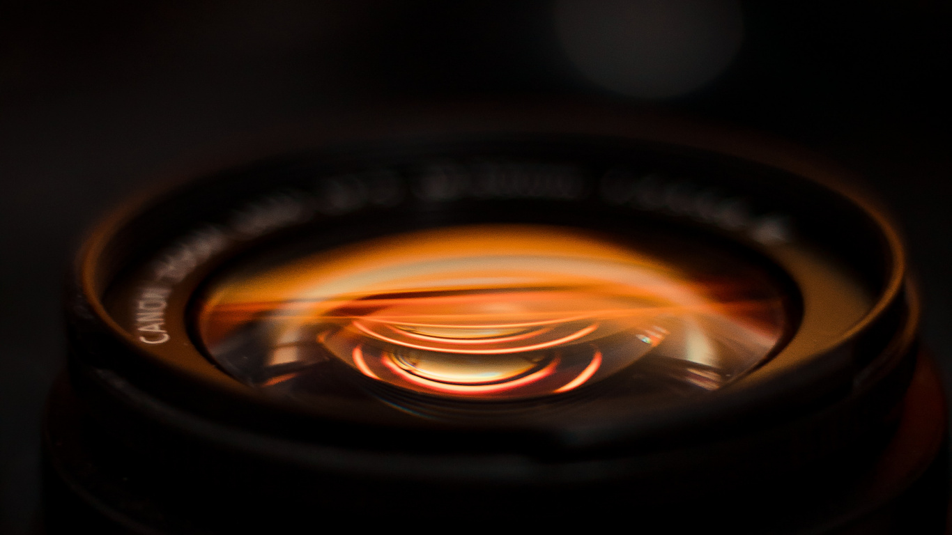 Black Camera Lens With Orange Light. Wallpaper in 1366x768 Resolution