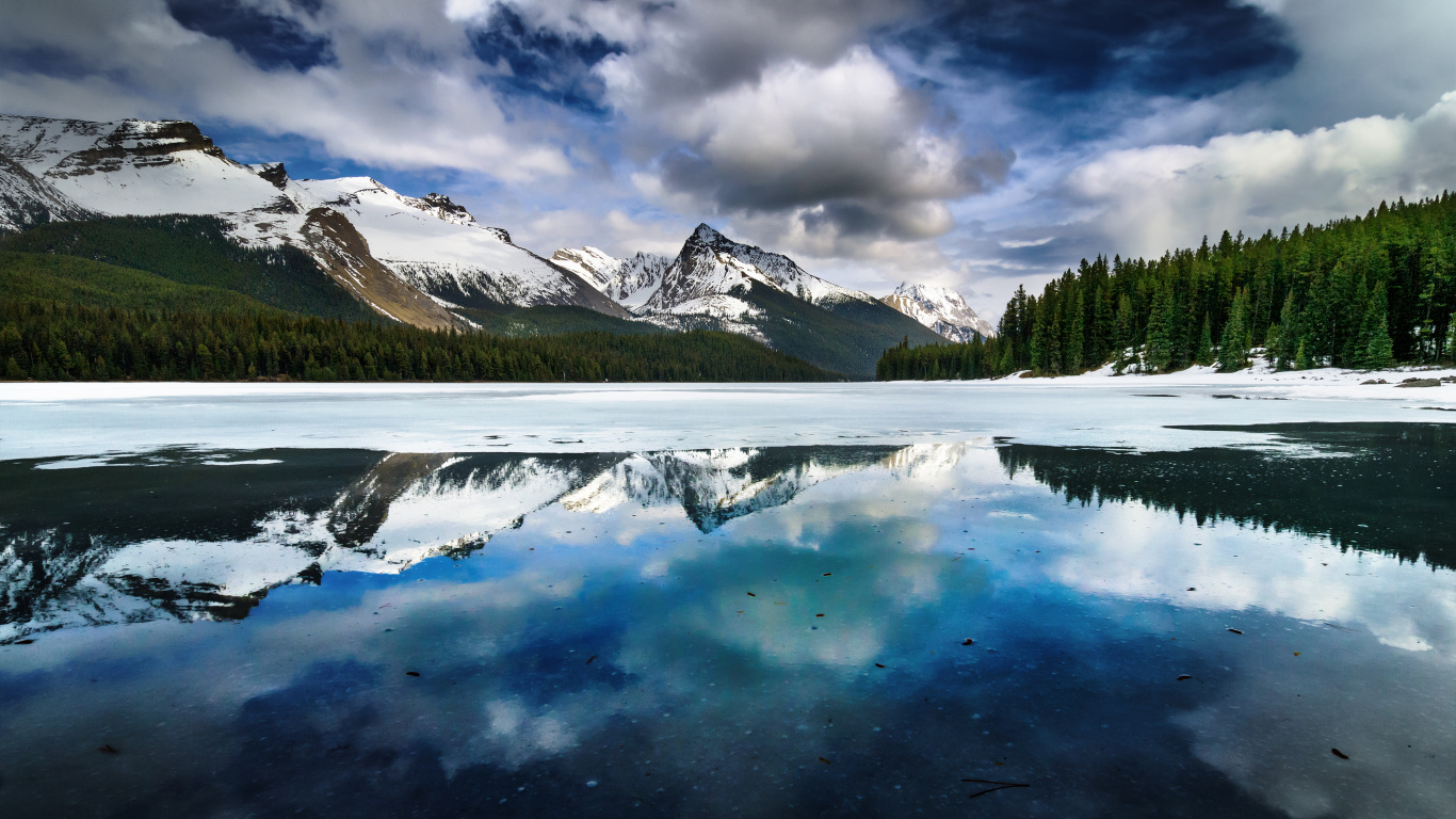 Snow Covered Mountain Near Green Pine Trees Under White Clouds and Blue Sky During Daytime. Wallpaper in 1366x768 Resolution