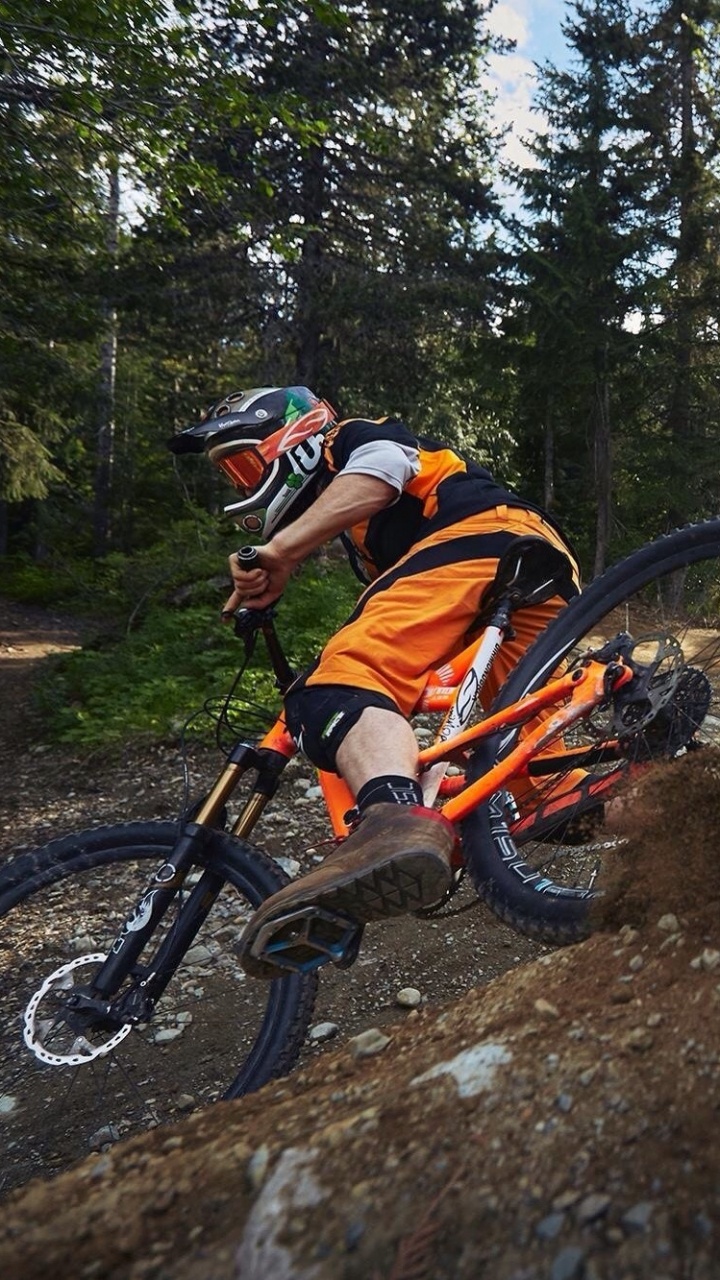 Mann in Orangefarbener Jacke, Der Auf Schwarzem Mountainbike Fährt Riding. Wallpaper in 720x1280 Resolution