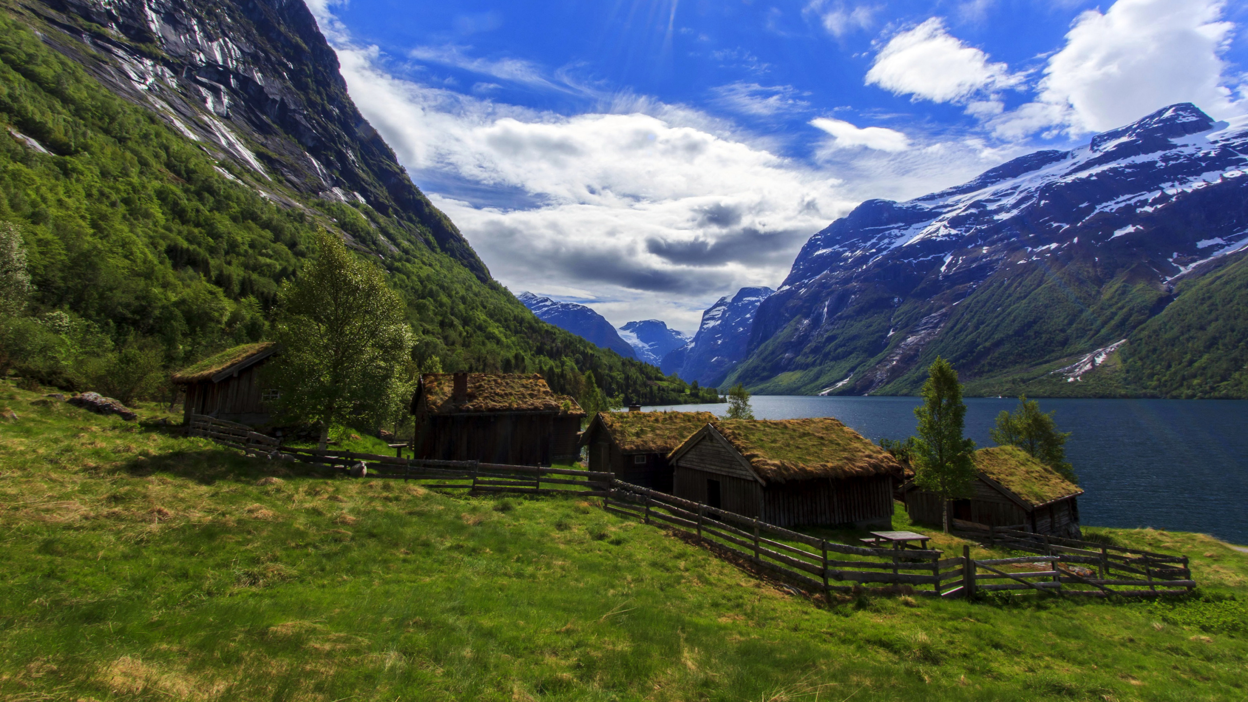 Brown Wooden House on Green Grass Field Near Mountain Under Blue Sky During Daytime. Wallpaper in 2560x1440 Resolution