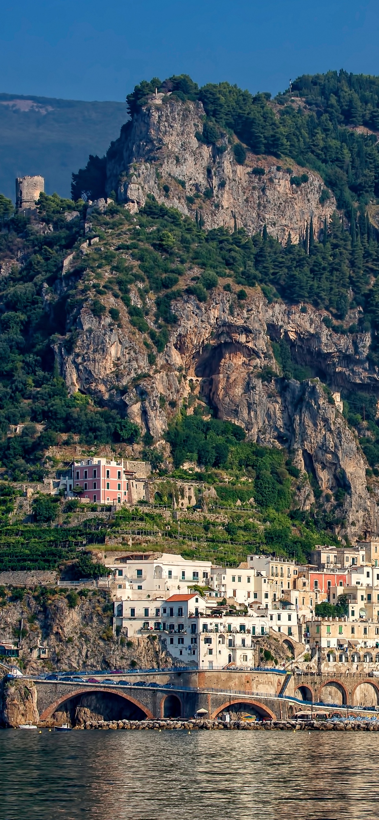 White and Brown Concrete Building Near Green Mountain During Daytime. Wallpaper in 1242x2688 Resolution