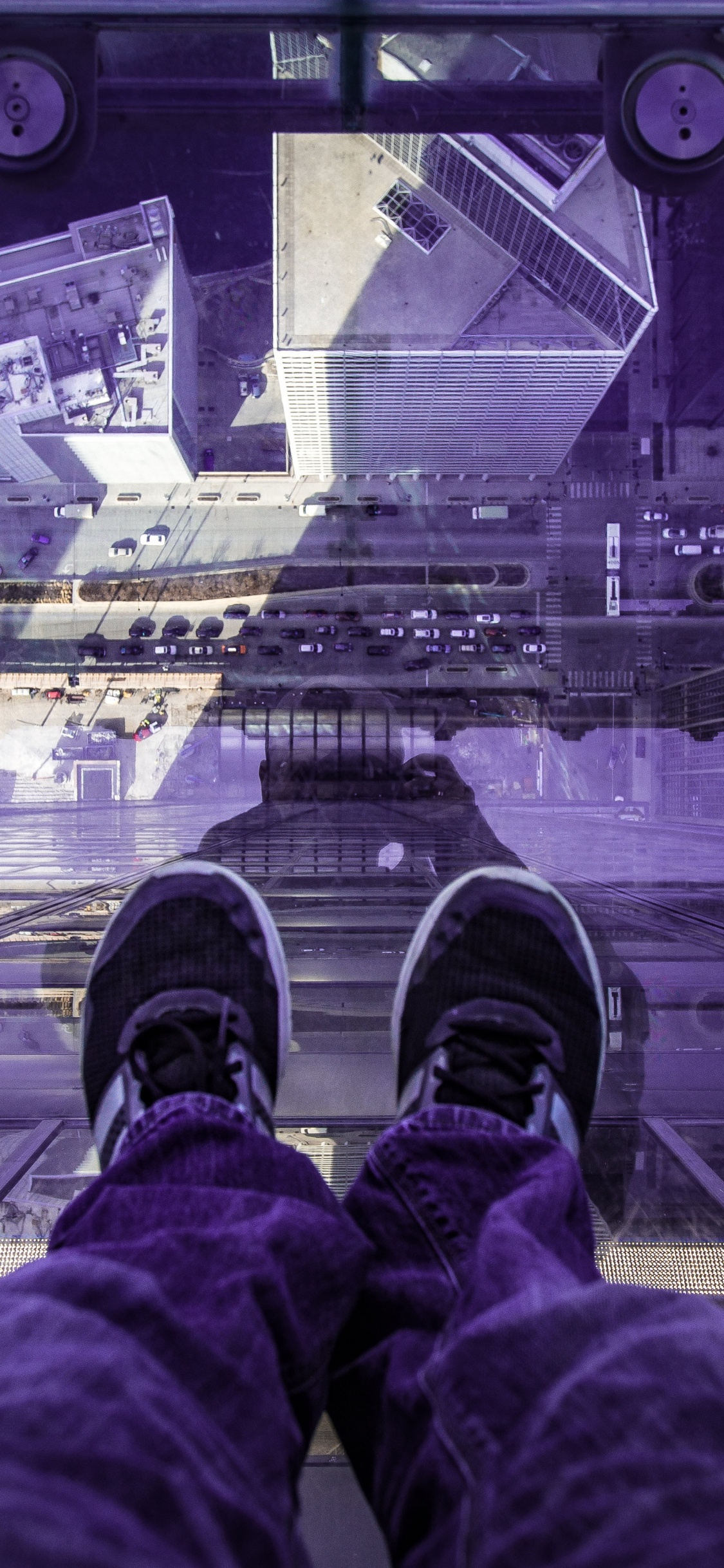 Person in Roten Hosen Und Schwarzen Schuhen, Die am Rand Eines Gebäudes Sitzt. Wallpaper in 1125x2436 Resolution