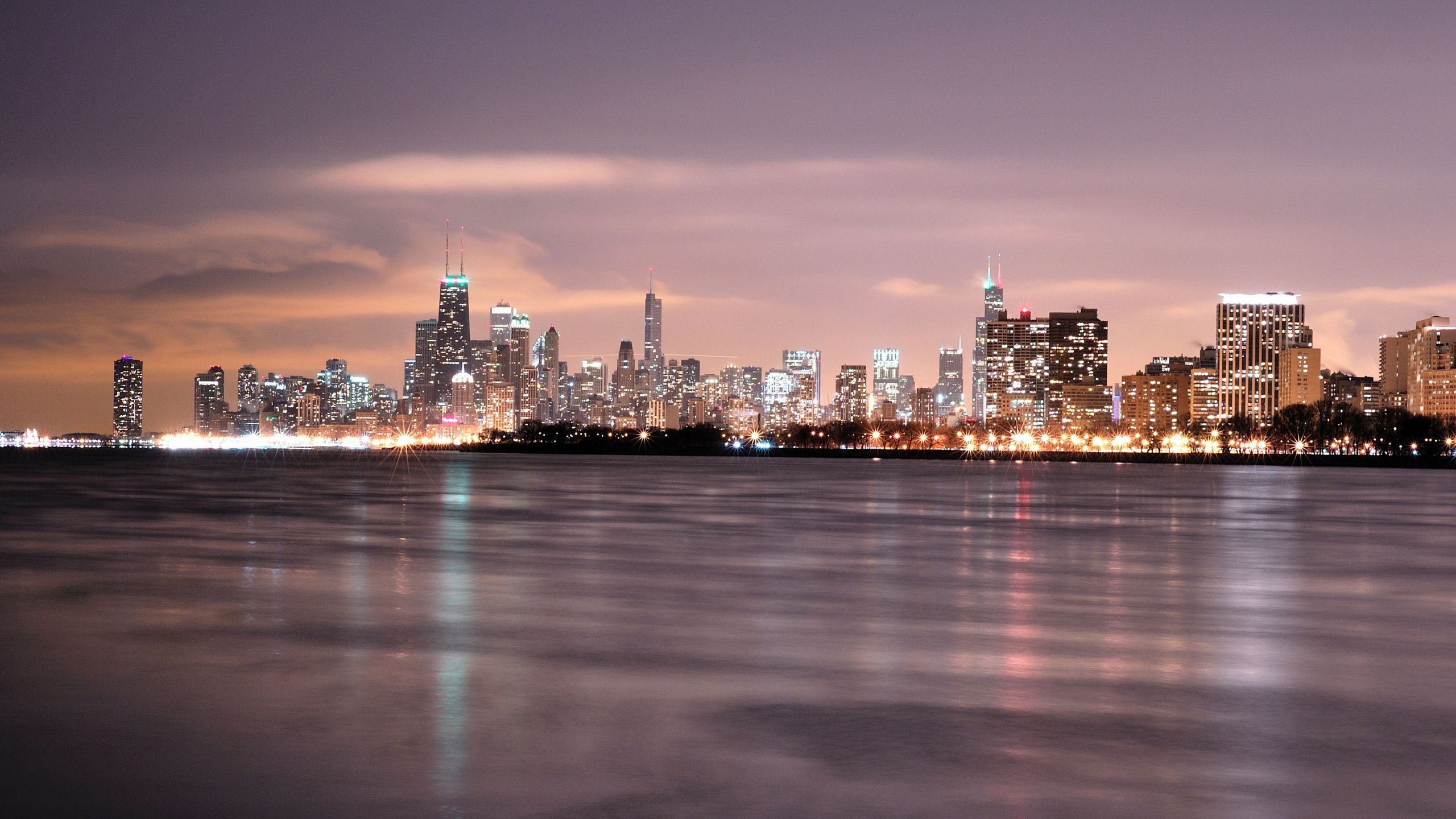Skyline Der Stadt Über Gewässer Während Der Nacht. Wallpaper in 2560x1440 Resolution