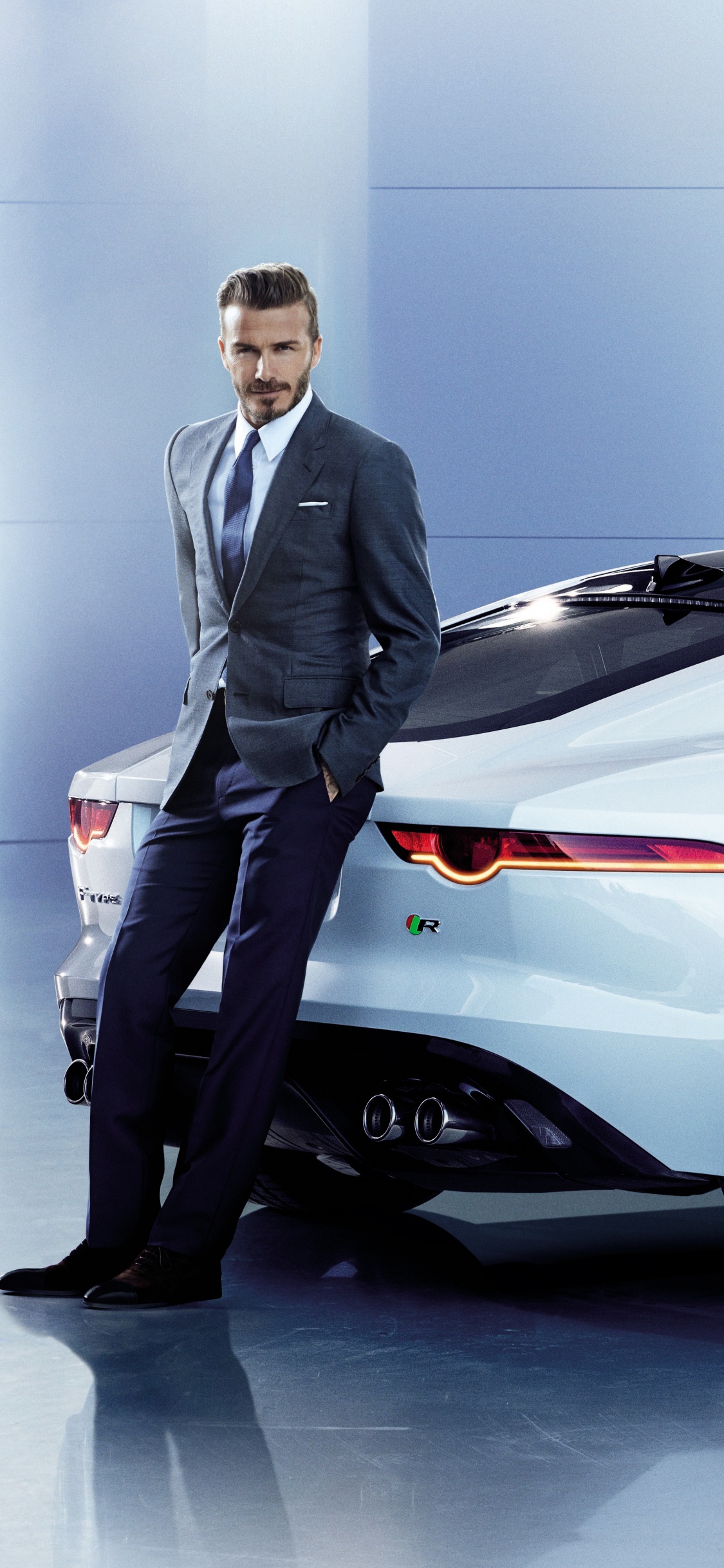 Man in Black Suit Standing Beside White Porsche 911 Coupe. Wallpaper in 1125x2436 Resolution