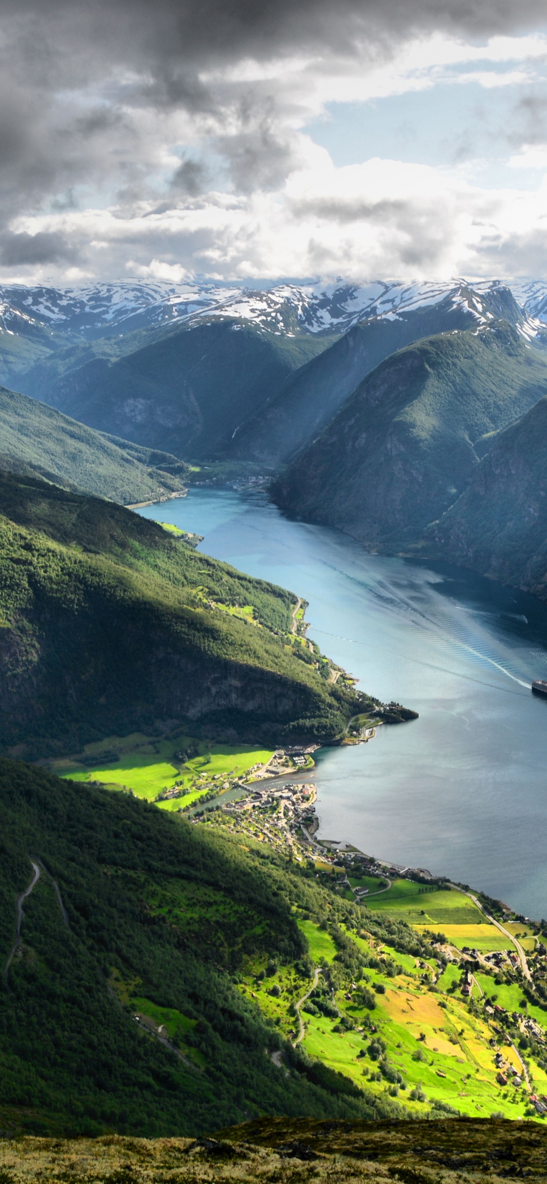 Green Mountains Near Body of Water Under White Clouds During Daytime. Wallpaper in 1125x2436 Resolution