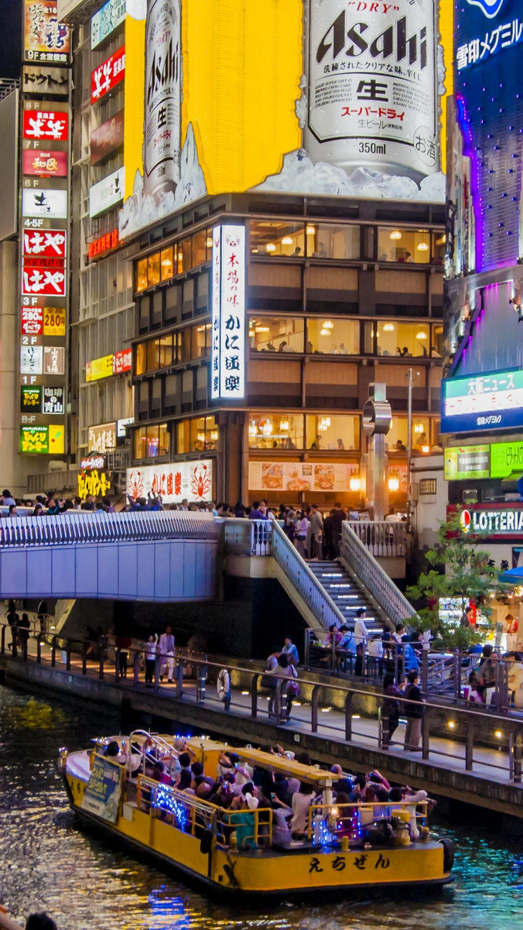 Gente Caminando en el Puente Cerca de Edificios de Gran Altura Durante la Noche. Wallpaper in 750x1334 Resolution
