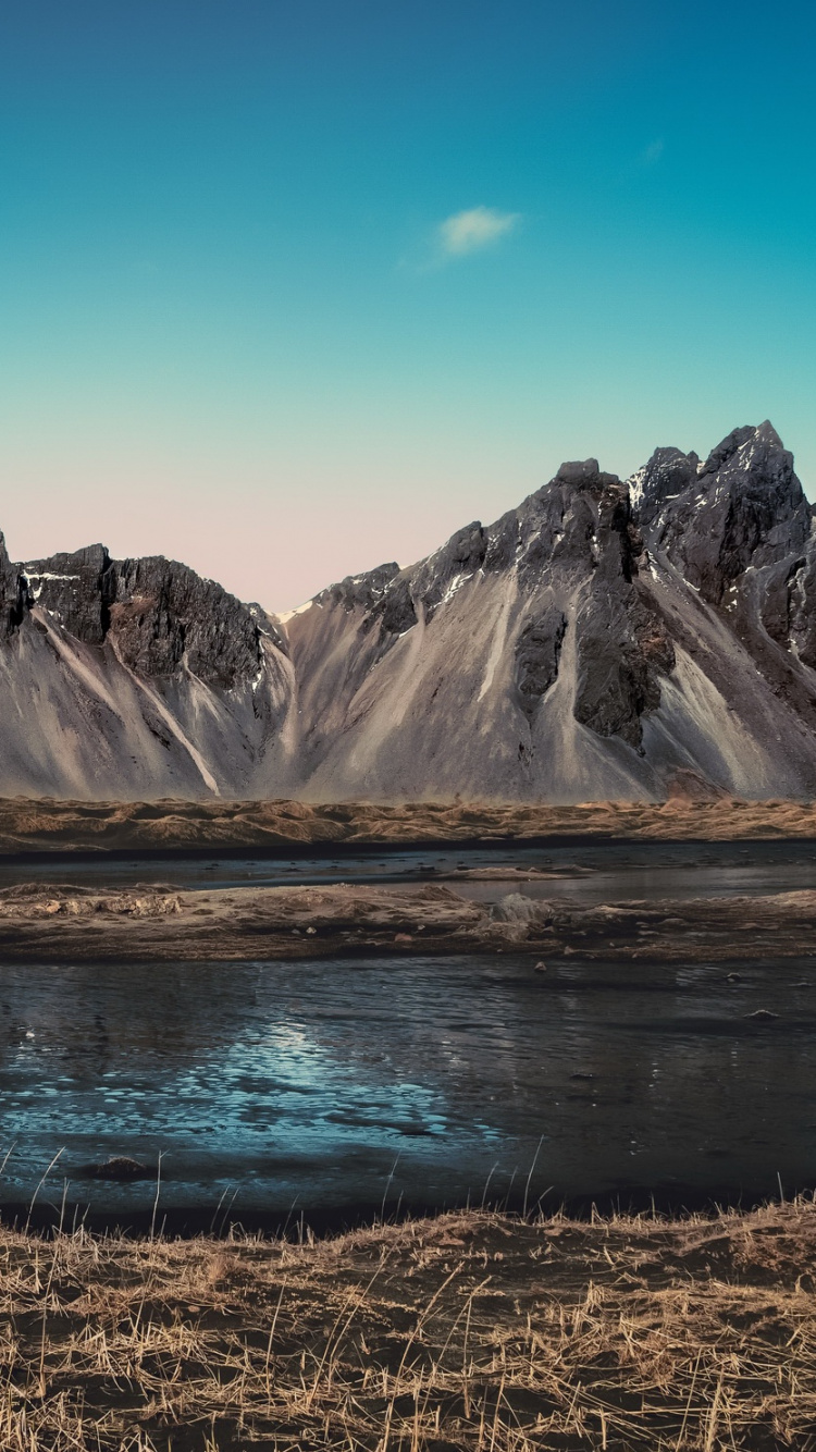 Montañas Marrones y Blancas Cerca Del Lago Bajo un Cielo Azul Durante el Día. Wallpaper in 750x1334 Resolution