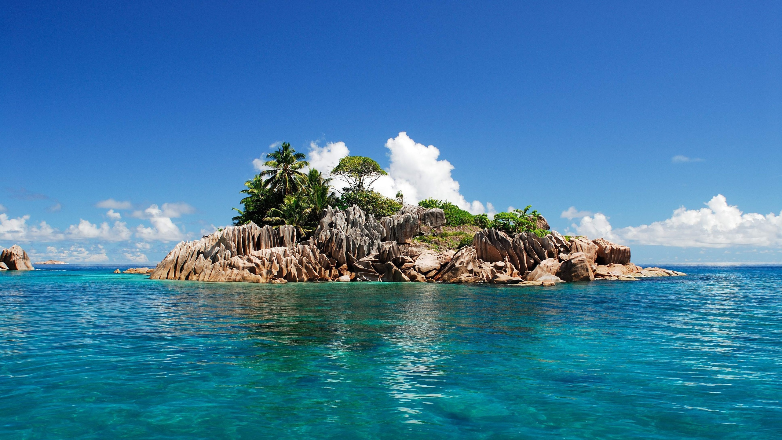 Brown Rocks on Body of Water Under Blue Sky During Daytime. Wallpaper in 2560x1440 Resolution