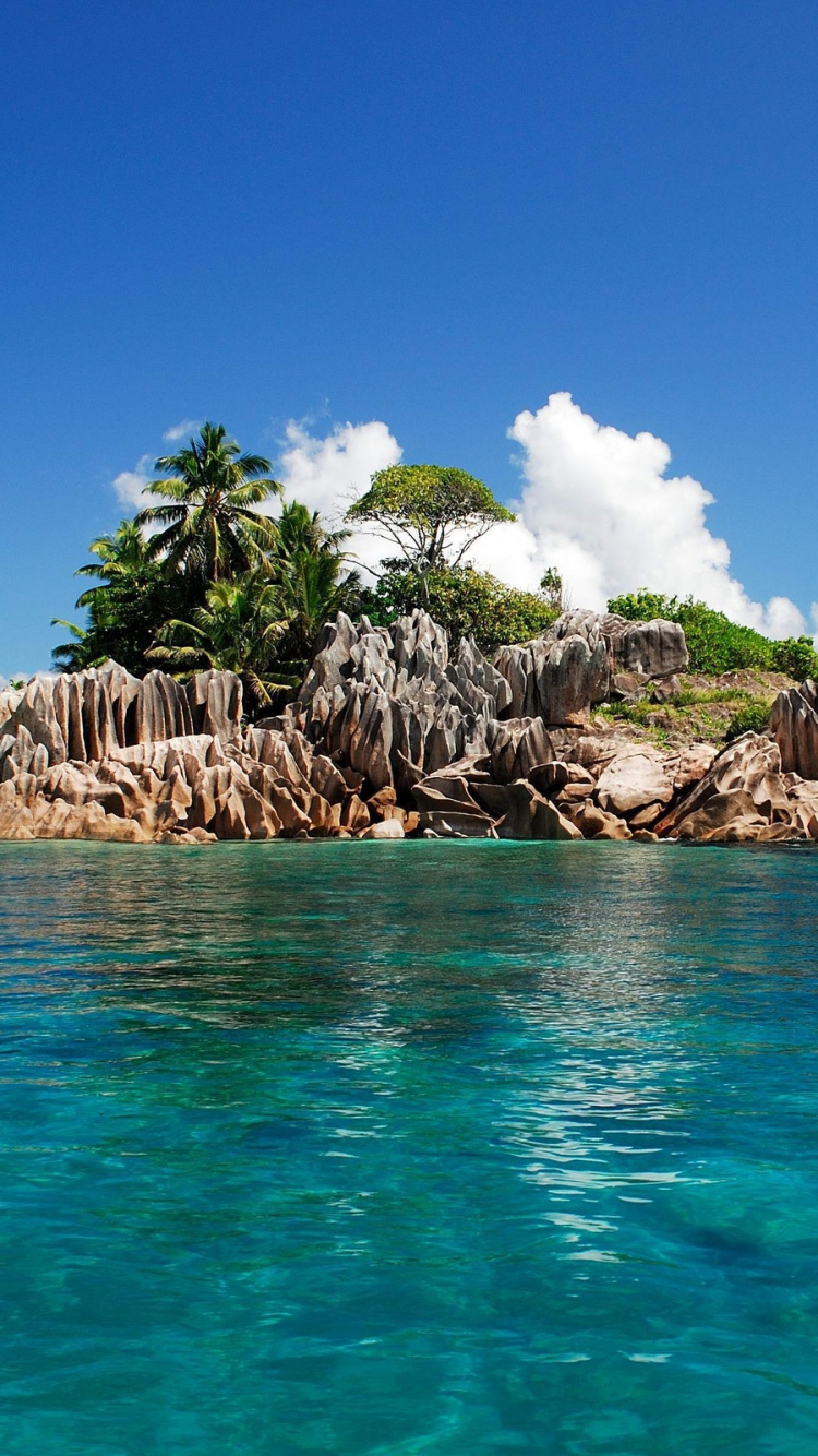 Brown Rocks on Body of Water Under Blue Sky During Daytime. Wallpaper in 750x1334 Resolution