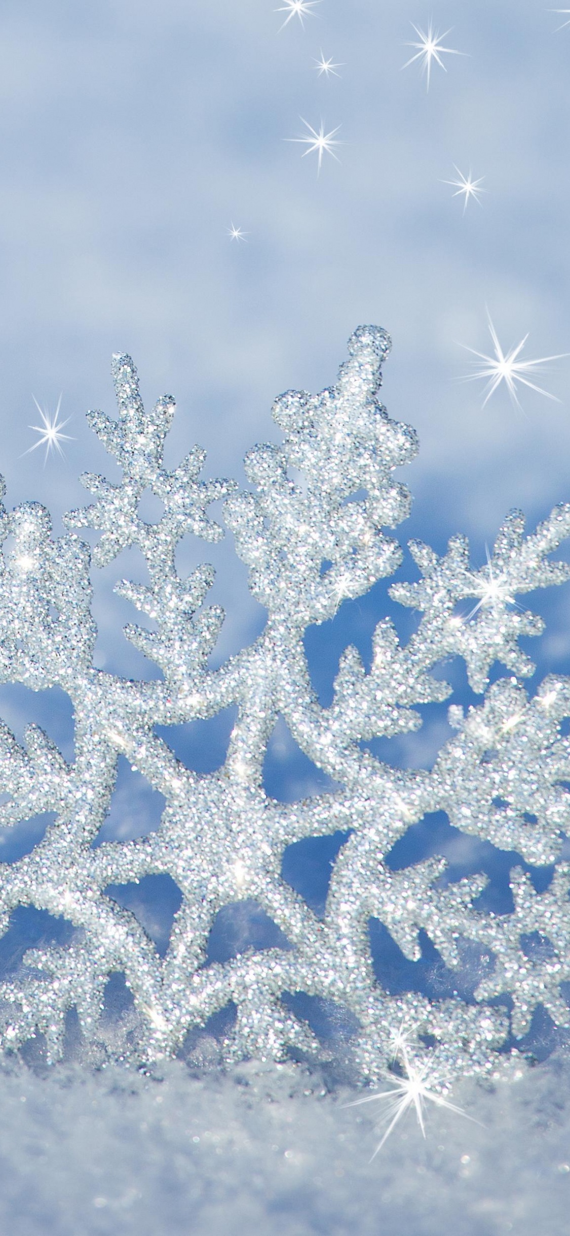 Copos de Nieve Blancos y Azules Sobre Arena Gris. Wallpaper in 1125x2436 Resolution