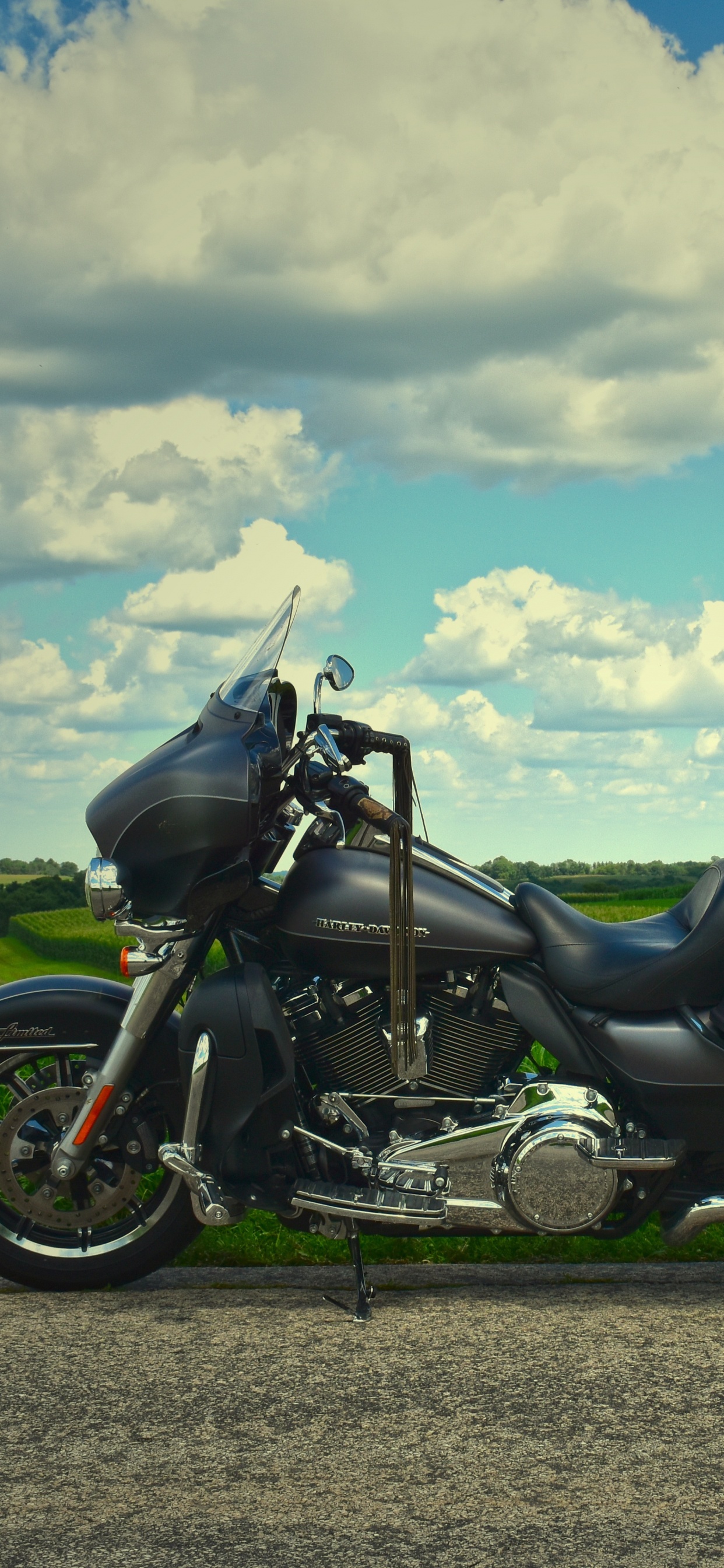 Black and White Sports Bike on Green Grass Field Under White Clouds and Blue Sky During. Wallpaper in 1242x2688 Resolution