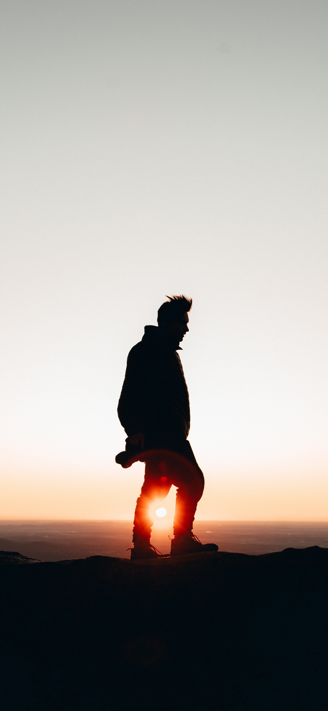 Silhouette de Personne Assise Sur un Rocher Pendant le Coucher du Soleil. Wallpaper in 1125x2436 Resolution