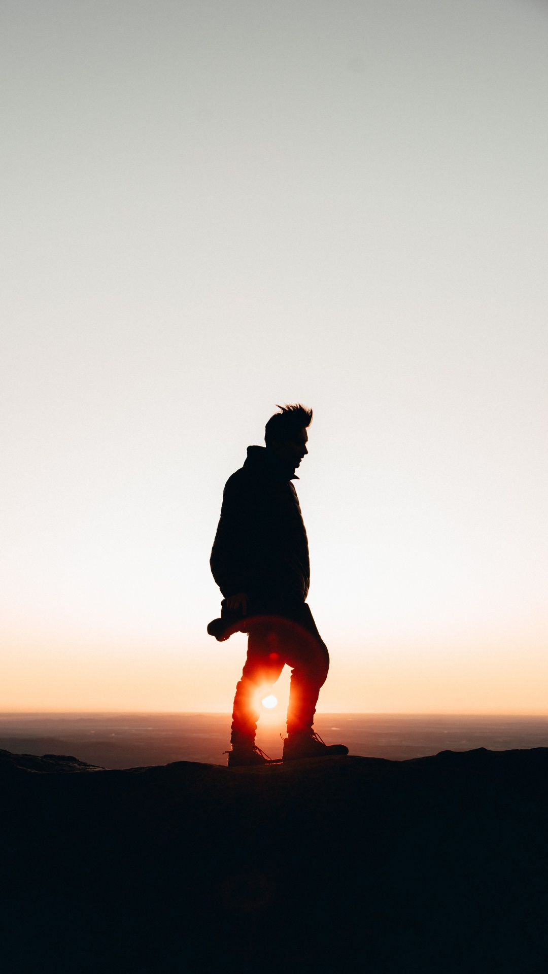 Silhouette Einer Person, Die Während Des Sonnenuntergangs Auf Einem Felsen Sitzt. Wallpaper in 1080x1920 Resolution