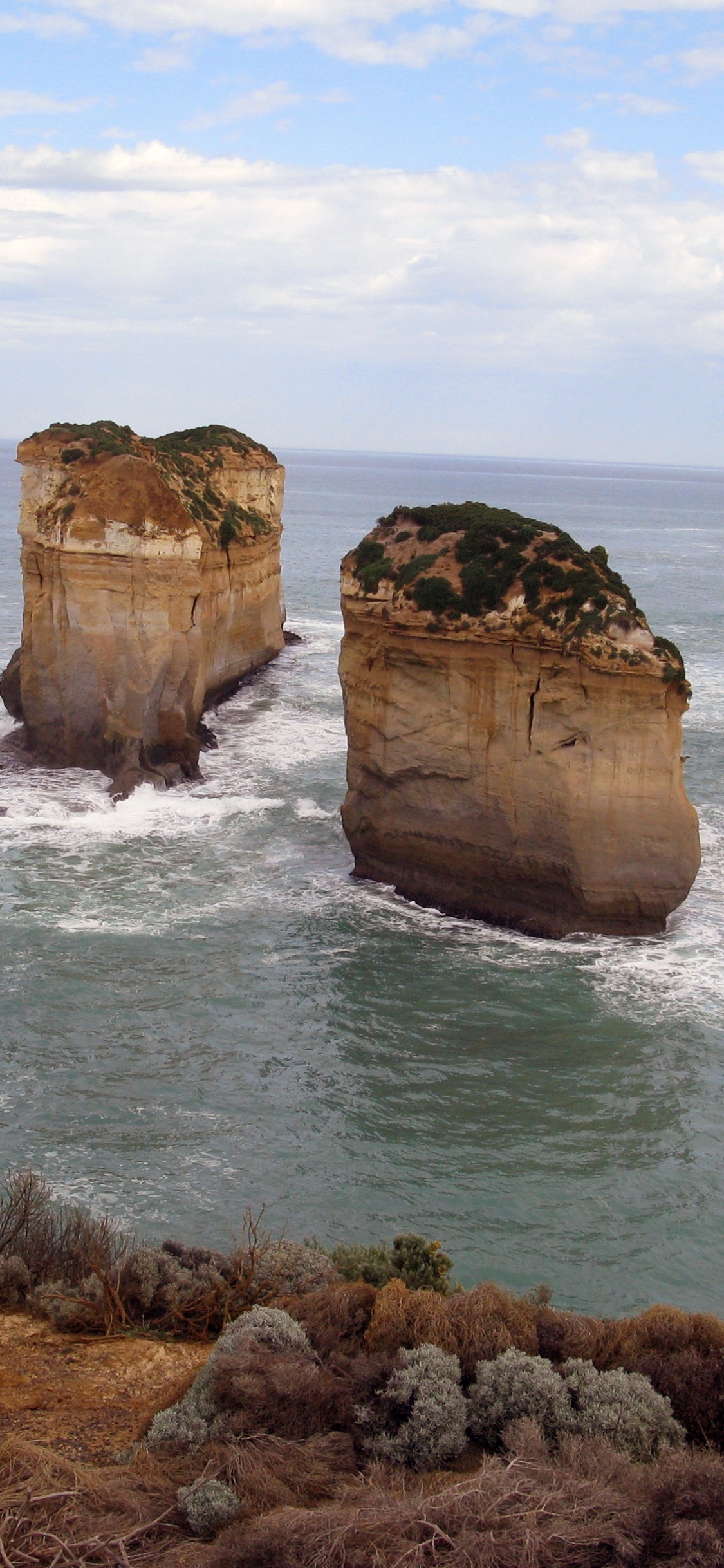 Formación de Roca Marrón en el Mar Durante el Día. Wallpaper in 1125x2436 Resolution