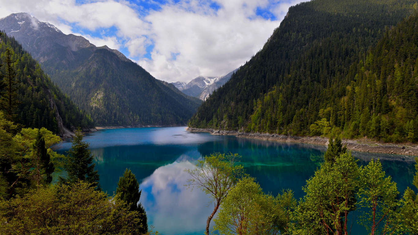 Montañas Verdes Junto al Lago Bajo un Cielo Azul y Nubes Blancas Durante el Día. Wallpaper in 1366x768 Resolution