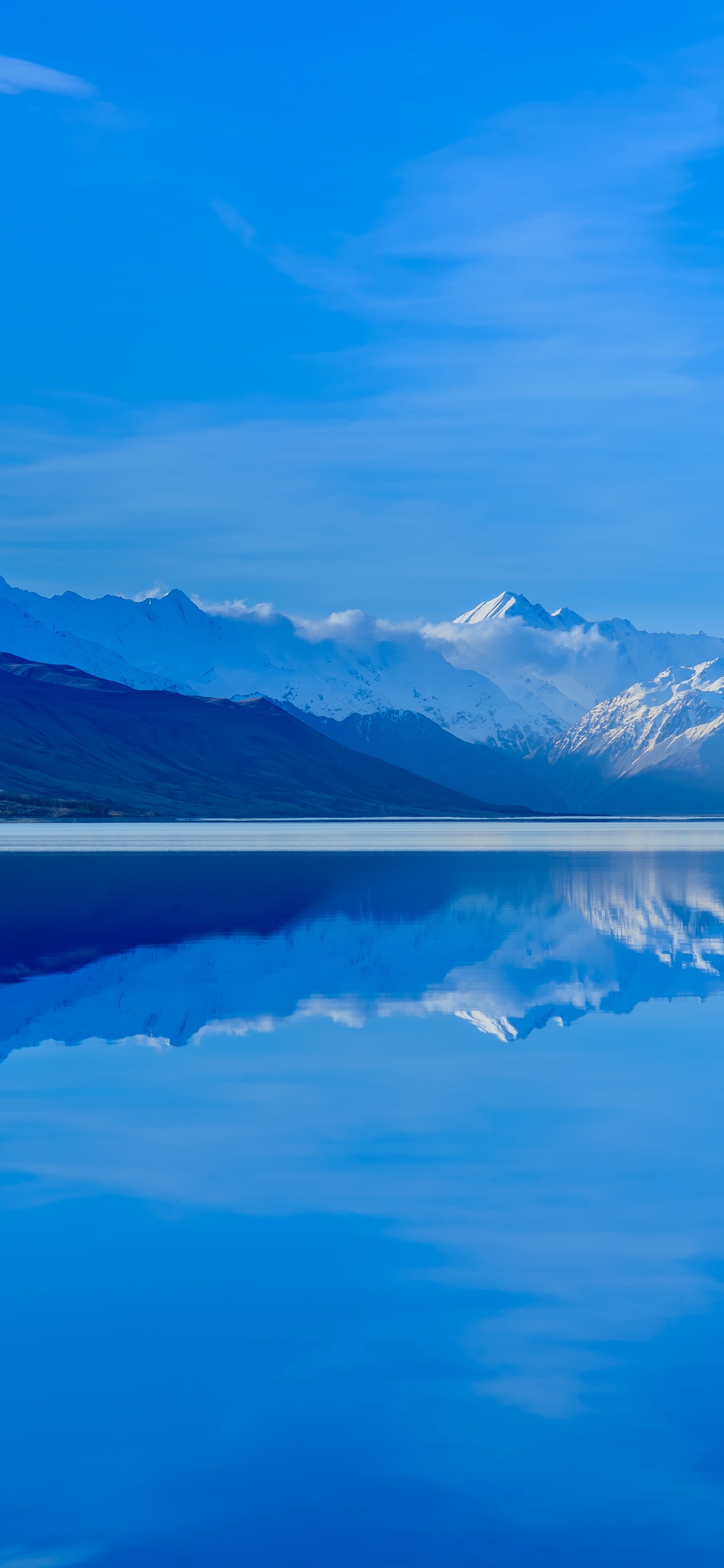 Cuerpo de Agua Cerca de la Montaña Bajo un Cielo Azul Durante el Día. Wallpaper in 1125x2436 Resolution