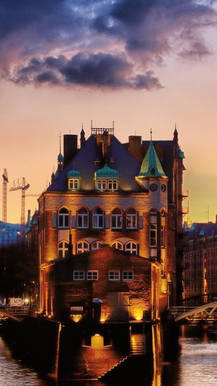 Braunes Und Grünes Betongebäude in Der Nähe Des Flusses Während Der Nachtzeit. Wallpaper in 720x1280 Resolution