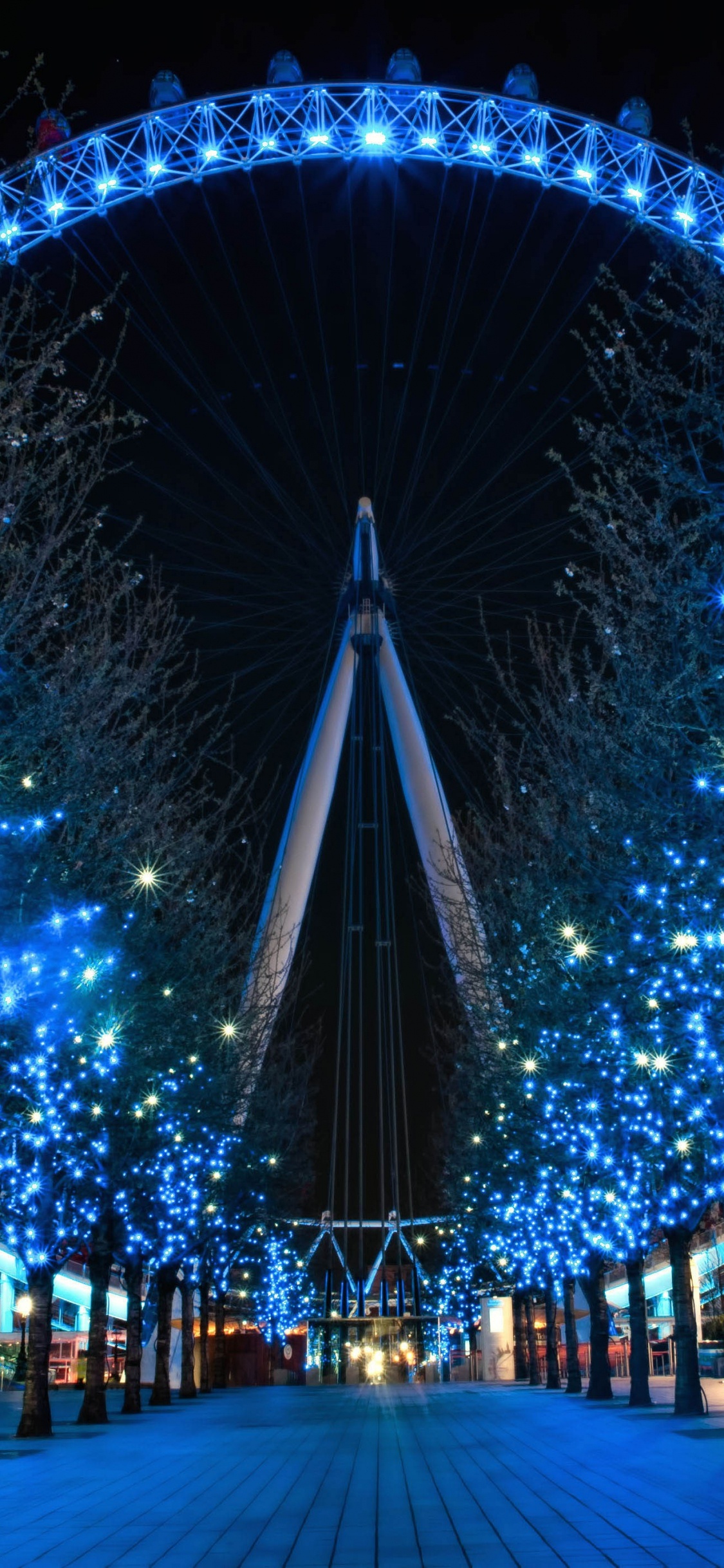 Blue String Lights on Street During Night Time. Wallpaper in 1125x2436 Resolution