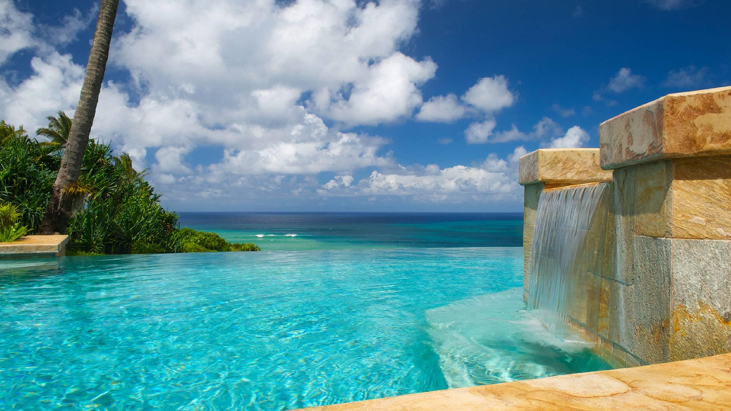 Green Trees Near Blue Sea Under Blue Sky and White Clouds During Daytime. Wallpaper in 2560x1440 Resolution