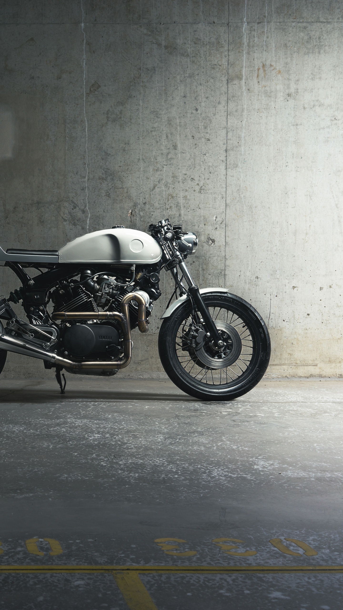 Schwarzes Und Silbernes Motorrad Neben Grauer Wand Geparkt. Wallpaper in 1440x2560 Resolution