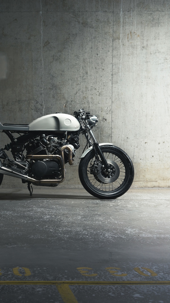 Schwarzes Und Silbernes Motorrad Neben Grauer Wand Geparkt. Wallpaper in 720x1280 Resolution