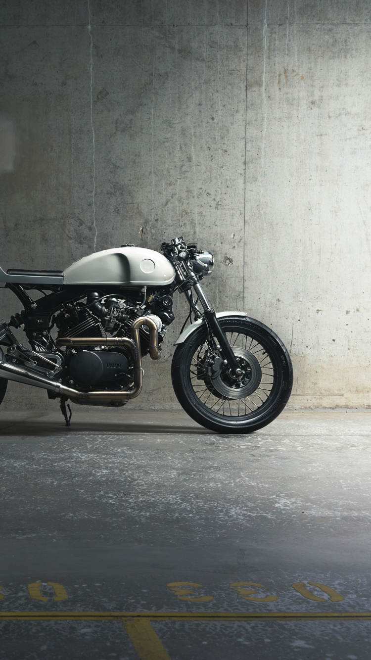 Schwarzes Und Silbernes Motorrad Neben Grauer Wand Geparkt. Wallpaper in 750x1334 Resolution