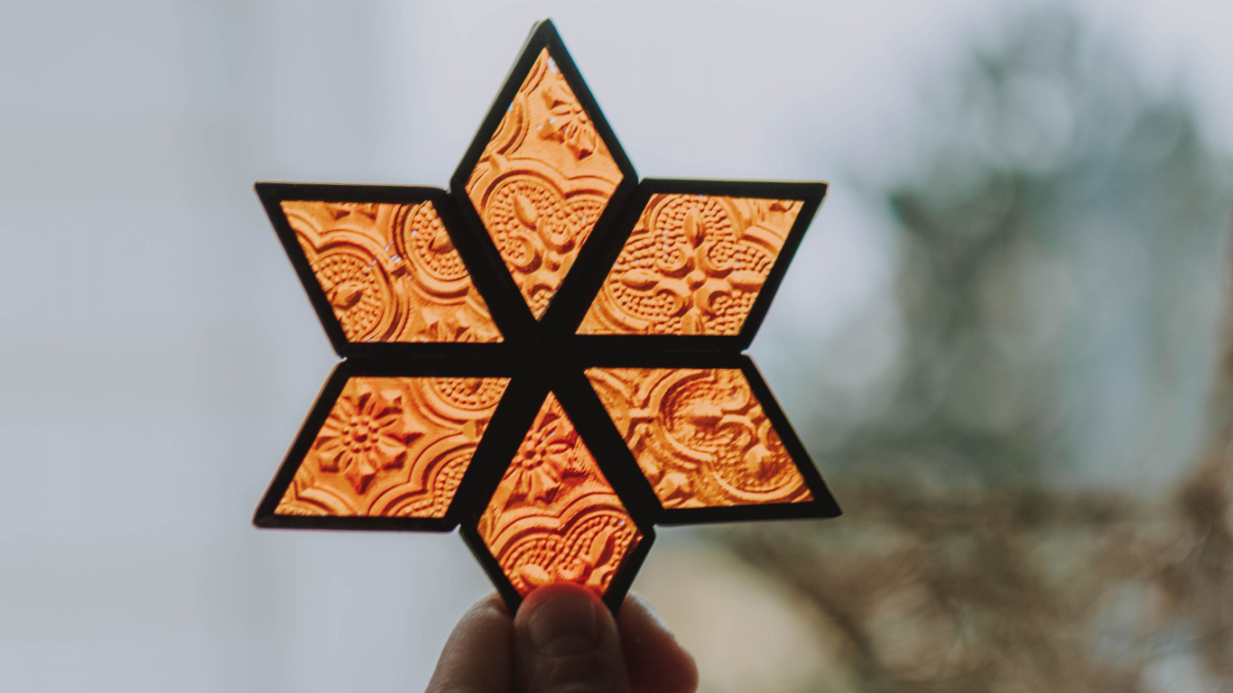 Person Holding Orange and Black Star Lantern. Wallpaper in 1366x768 Resolution