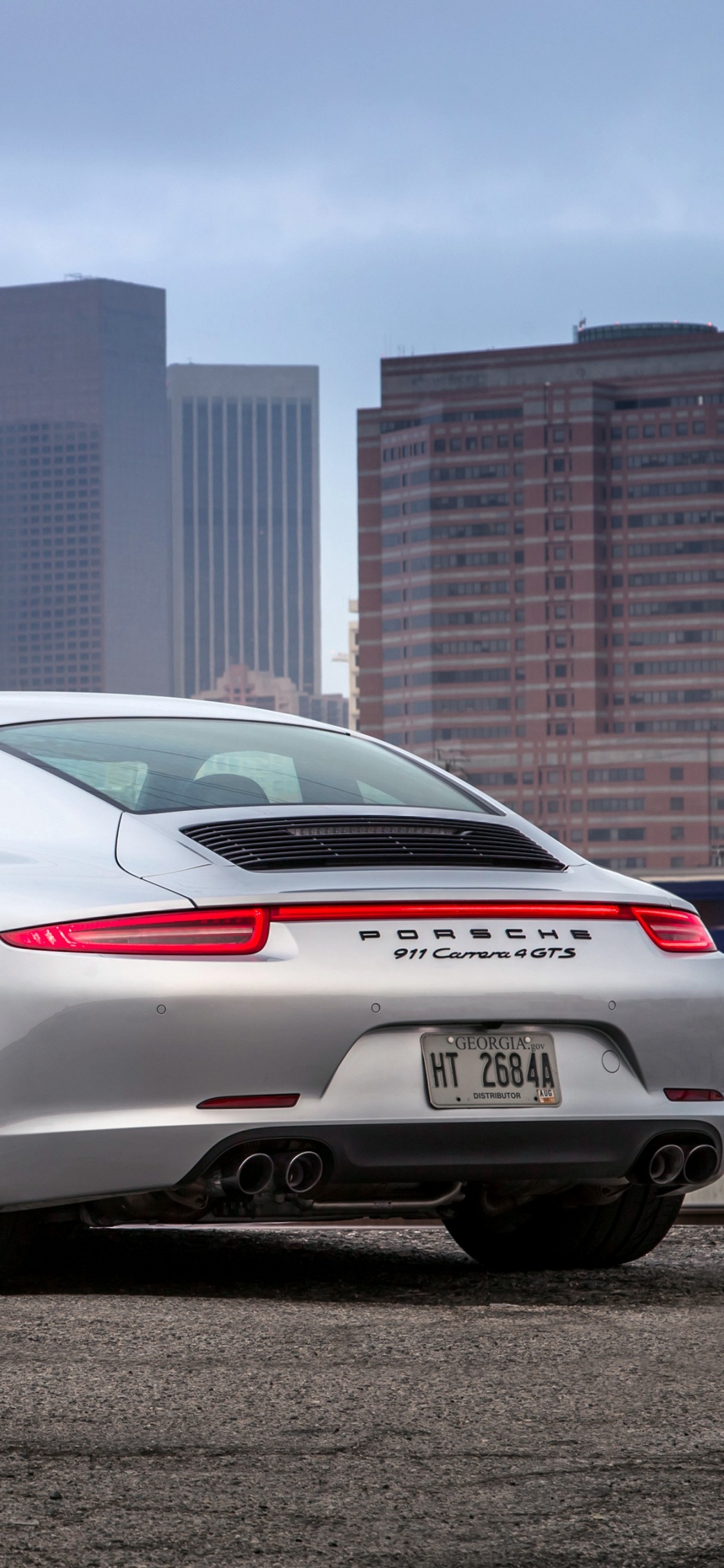 Porsche 911 Blanche Garée Près D'une Clôture Métallique Bleue Pendant la Journée. Wallpaper in 1125x2436 Resolution
