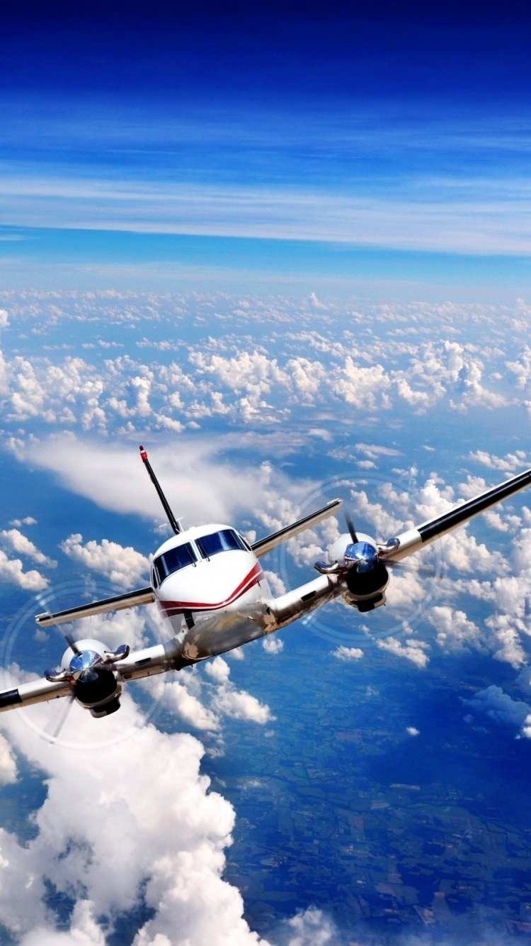 Weißes Und Schwarzes Flugzeug, Das Tagsüber Über Weiße Wolken Fliegt. Wallpaper in 750x1334 Resolution