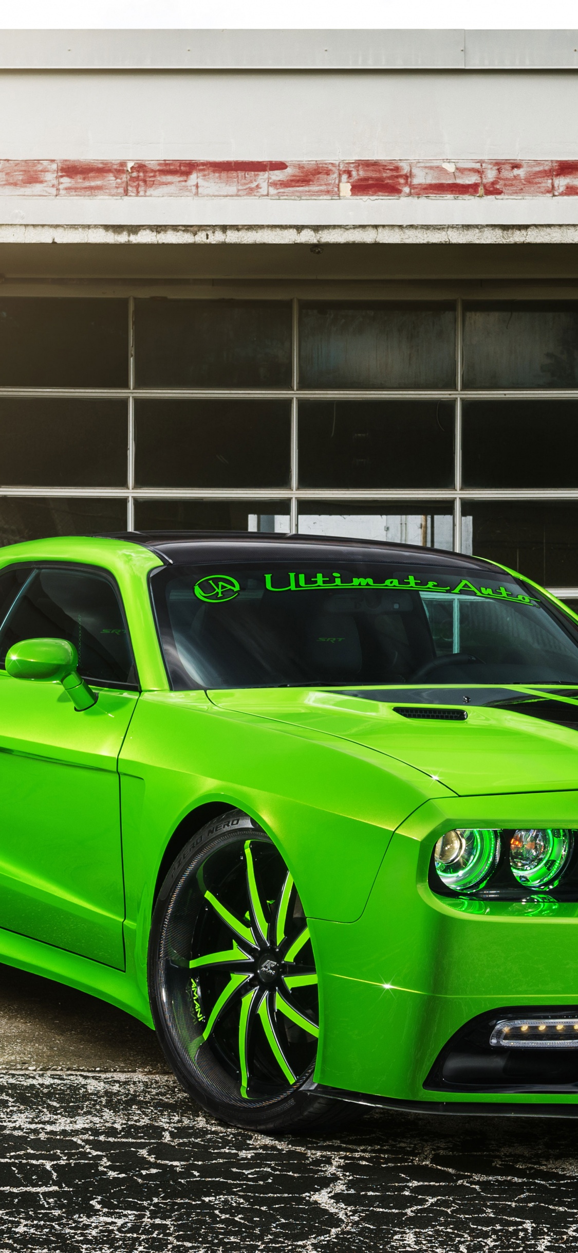 Chevrolet Camaro Verde Estacionado Junto al Edificio de Hormigón Blanco Durante el Día. Wallpaper in 1125x2436 Resolution