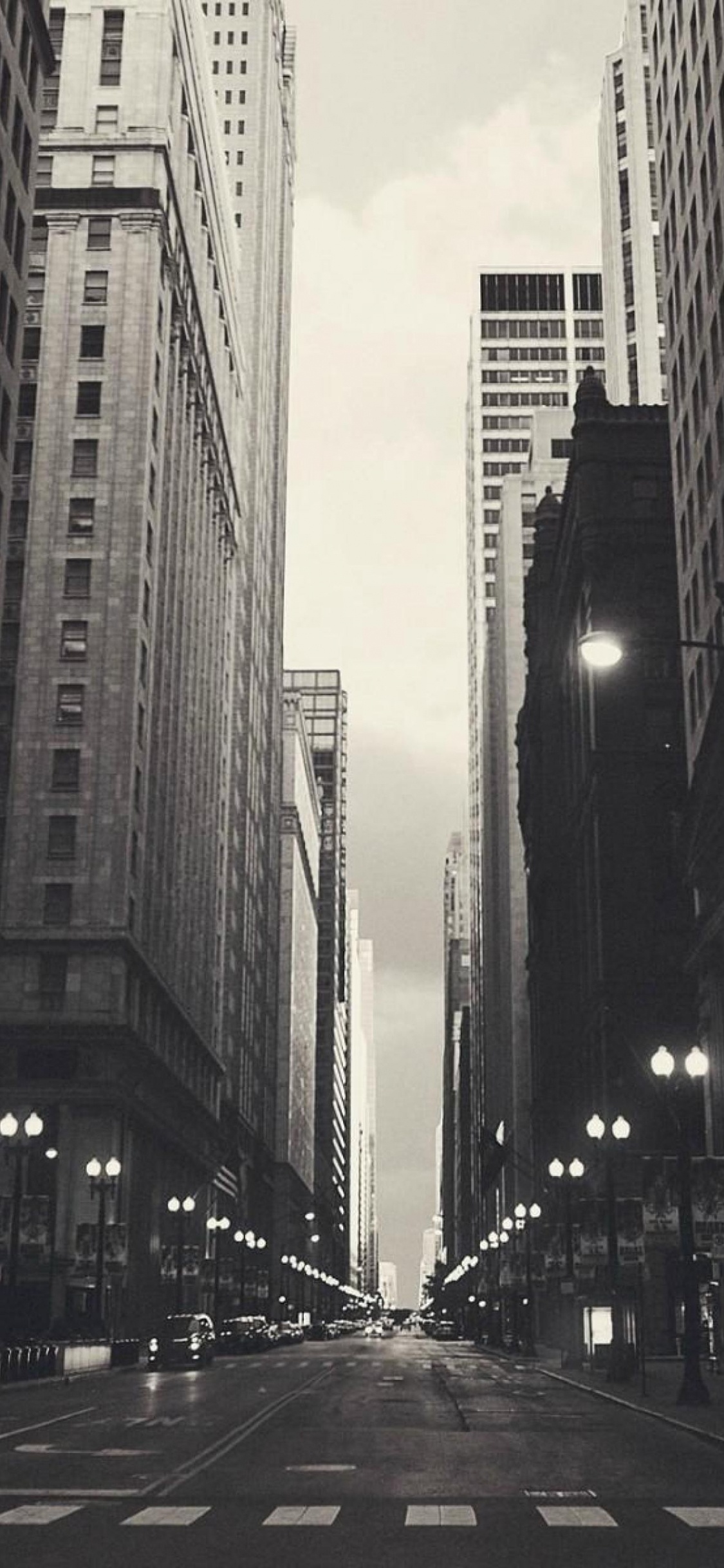 Menschen, Die Tagsüber Zwischen Hochhäusern Auf Der Straße Gehen. Wallpaper in 1125x2436 Resolution