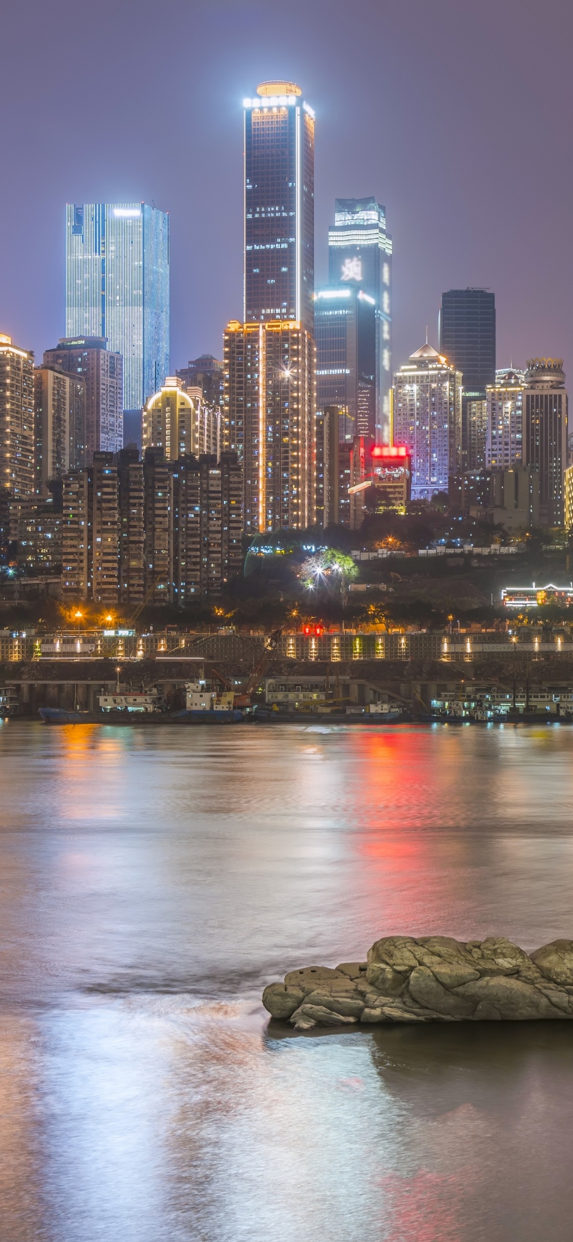 City Skyline Across Body of Water During Night Time. Wallpaper in 1125x2436 Resolution
