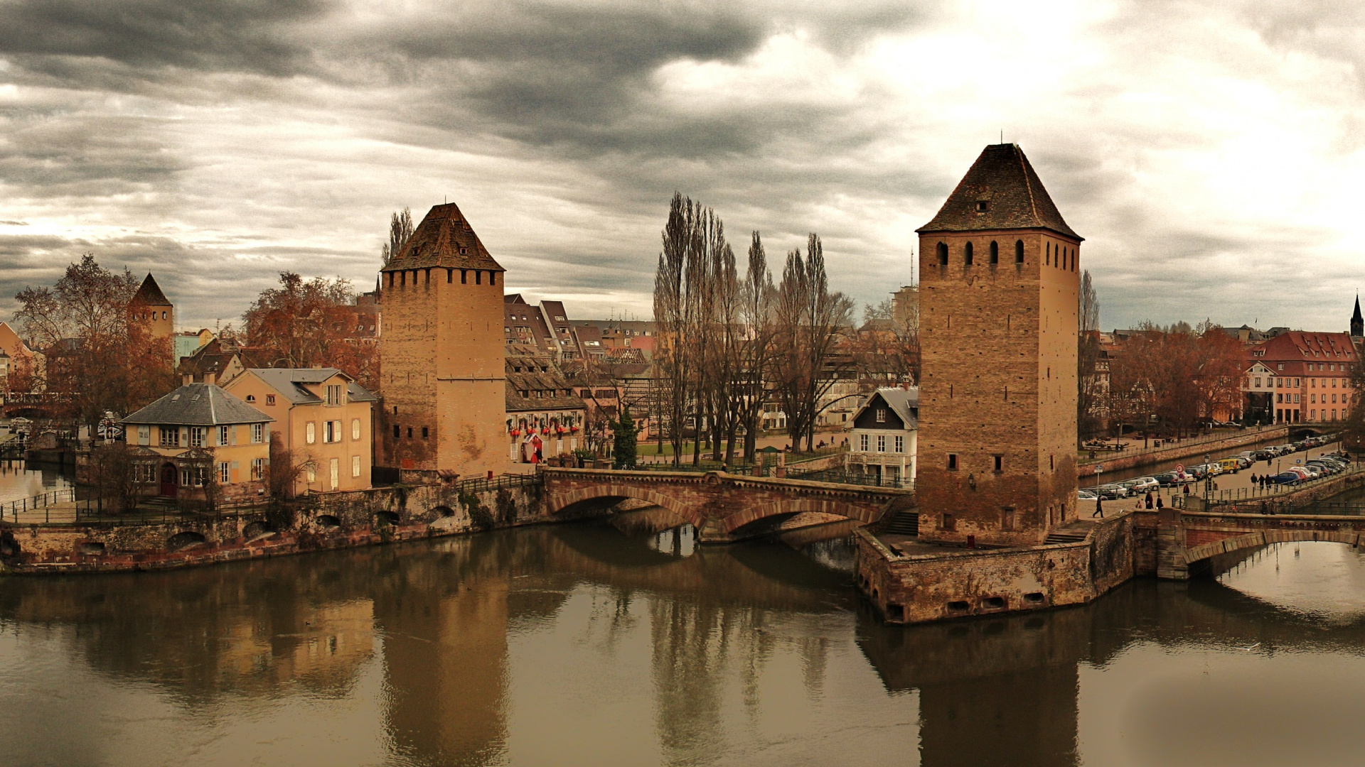 Brown Brick Building Beside River Under Cloudy Sky. Wallpaper in 1920x1080 Resolution