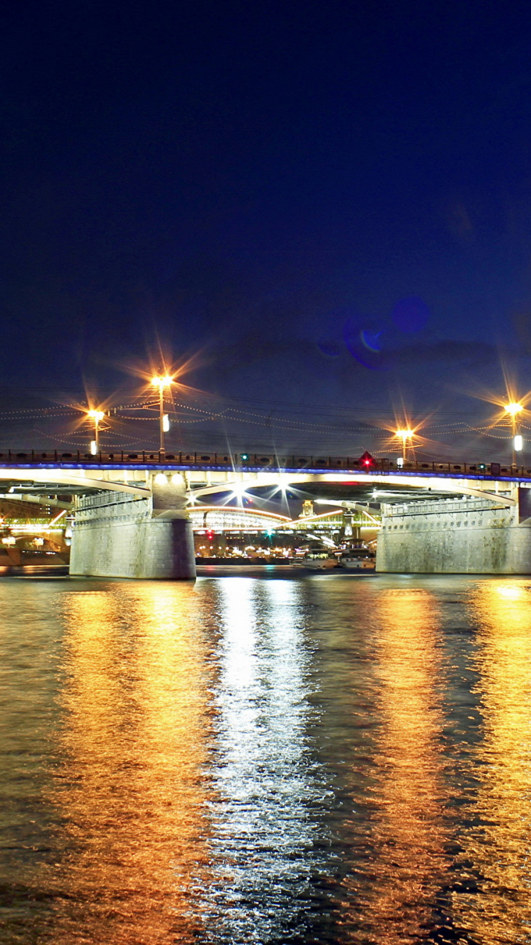 Beleuchtete Brücke Über Den Fluss Während Der Nacht. Wallpaper in 750x1334 Resolution