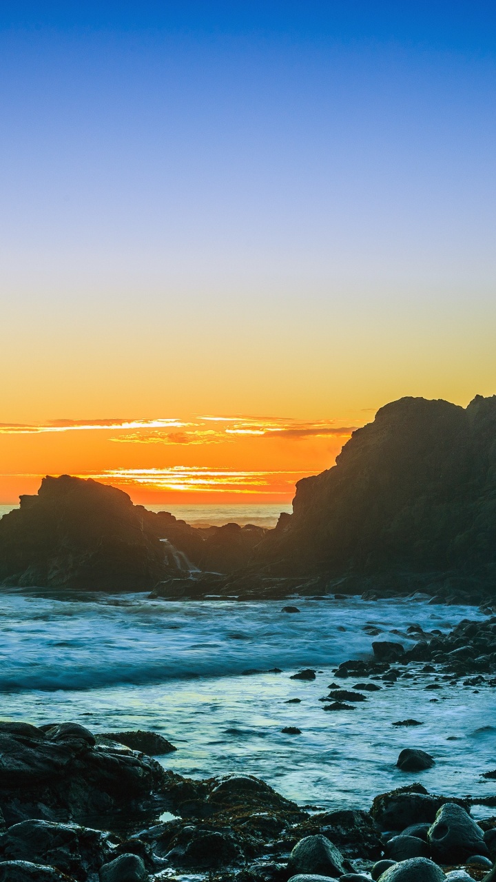 Ocean Waves Crashing on Rocks During Sunset. Wallpaper in 720x1280 Resolution