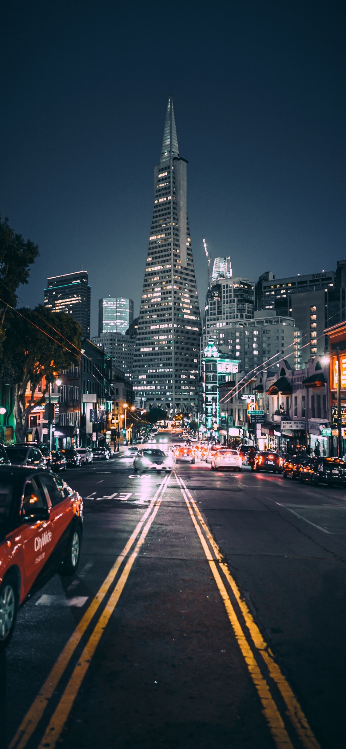 Cars on Road Near High Rise Buildings During Night Time. Wallpaper in 1125x2436 Resolution