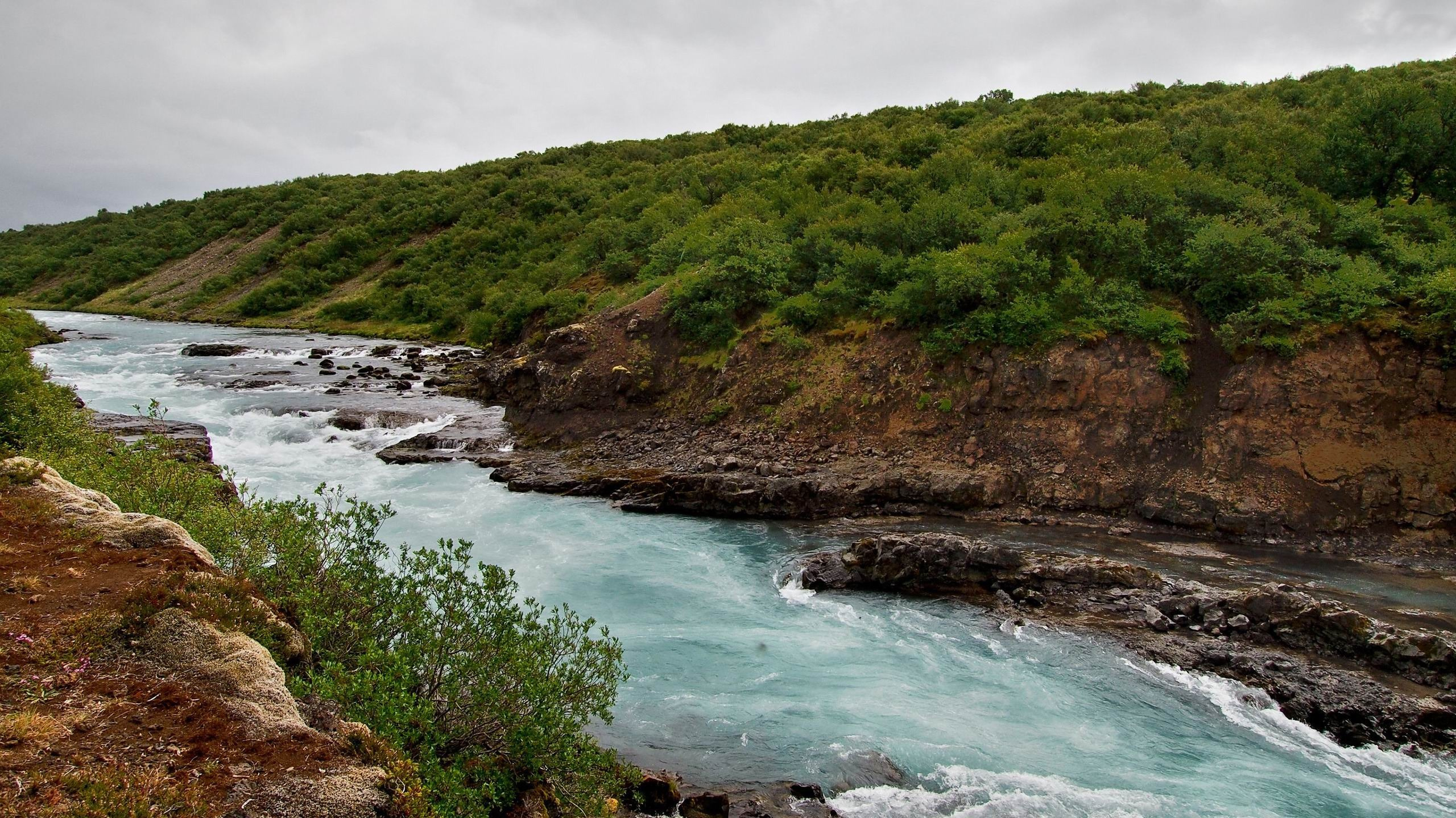 Montaña Verde y Marrón Junto al Cuerpo de Agua Durante el Día.. Wallpaper in 2560x1440 Resolution