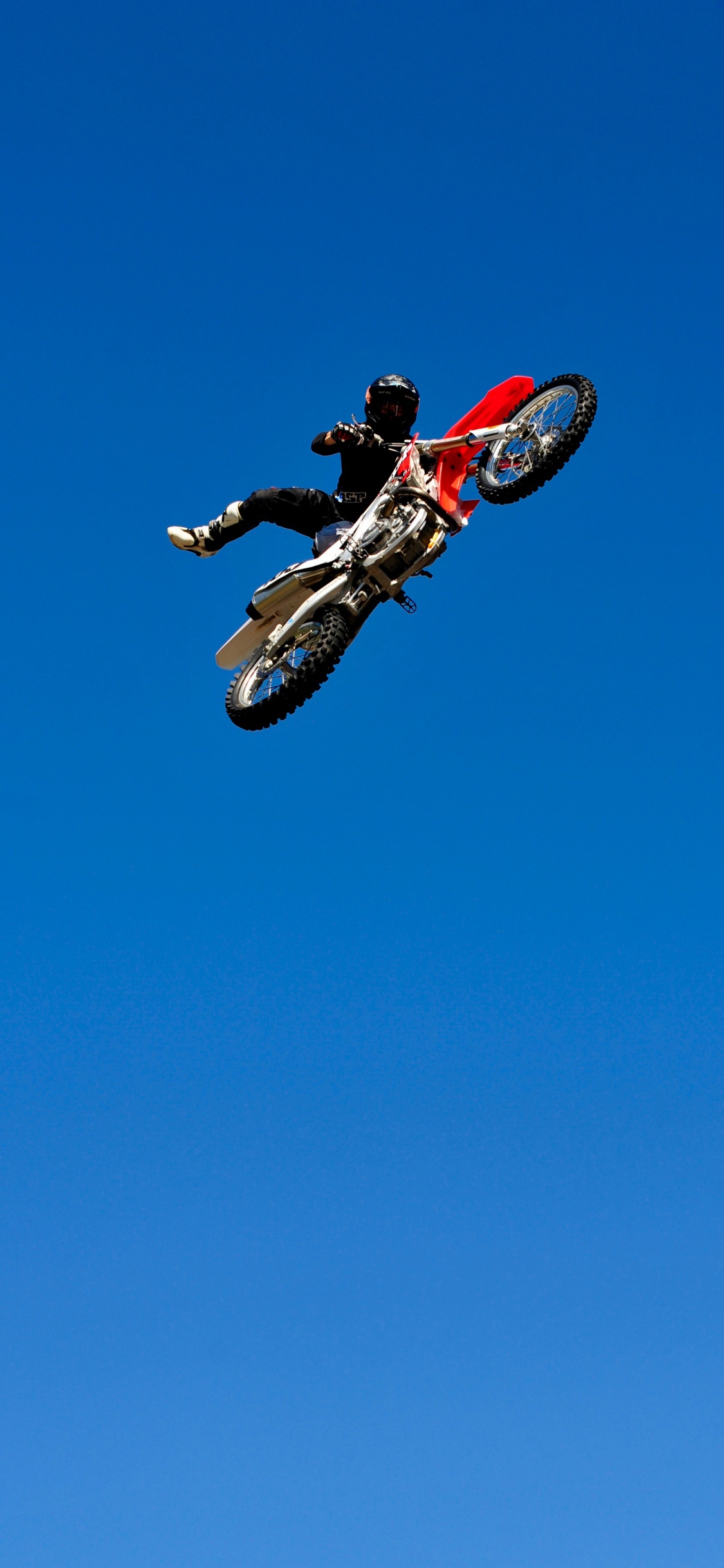 Man in Red and Black Motocross Suit Riding Red and White Motocross Dirt Bike. Wallpaper in 1125x2436 Resolution