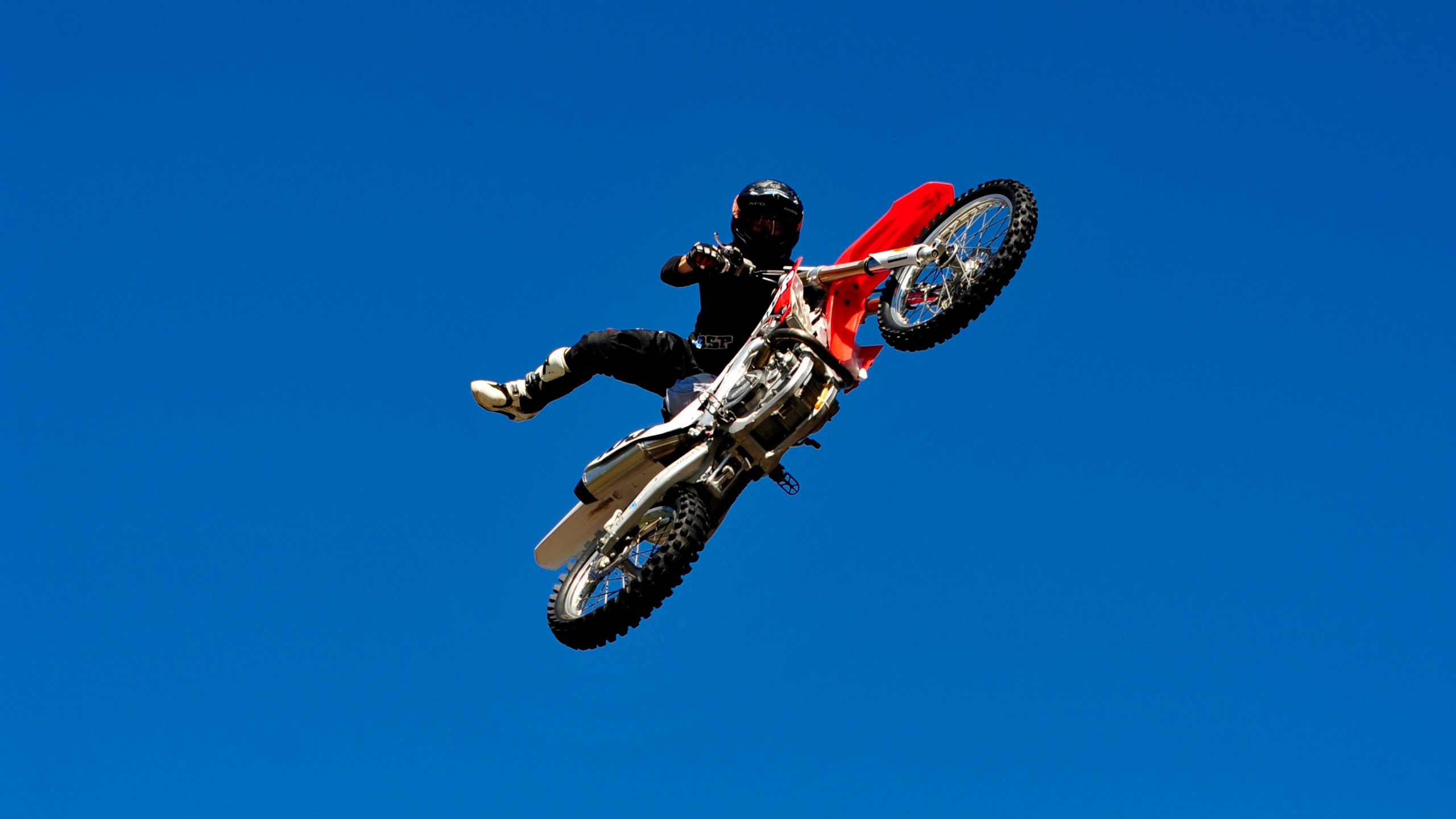 Man in Red and Black Motocross Suit Riding Red and White Motocross Dirt Bike. Wallpaper in 2560x1440 Resolution