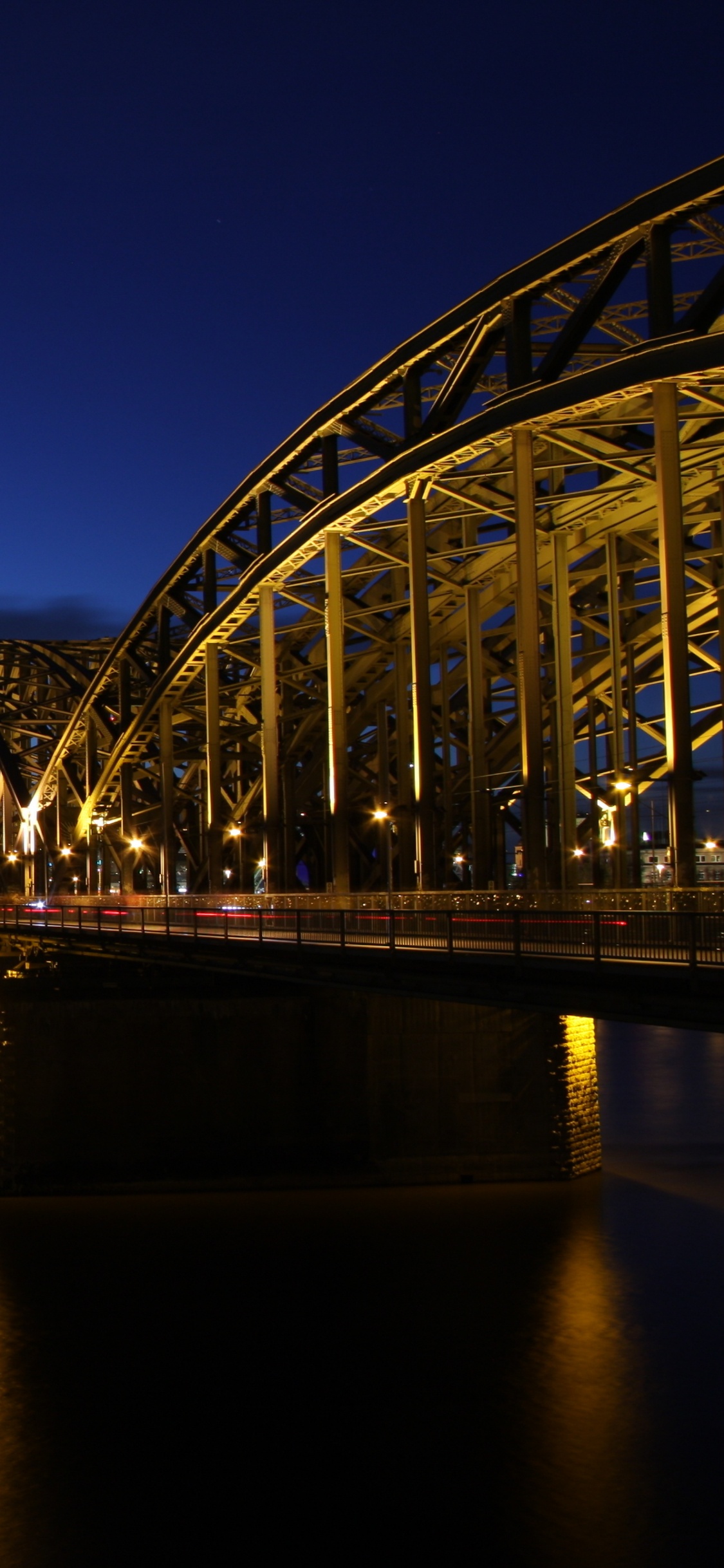 Lighted Bridge Over Water During Night Time. Wallpaper in 1125x2436 Resolution